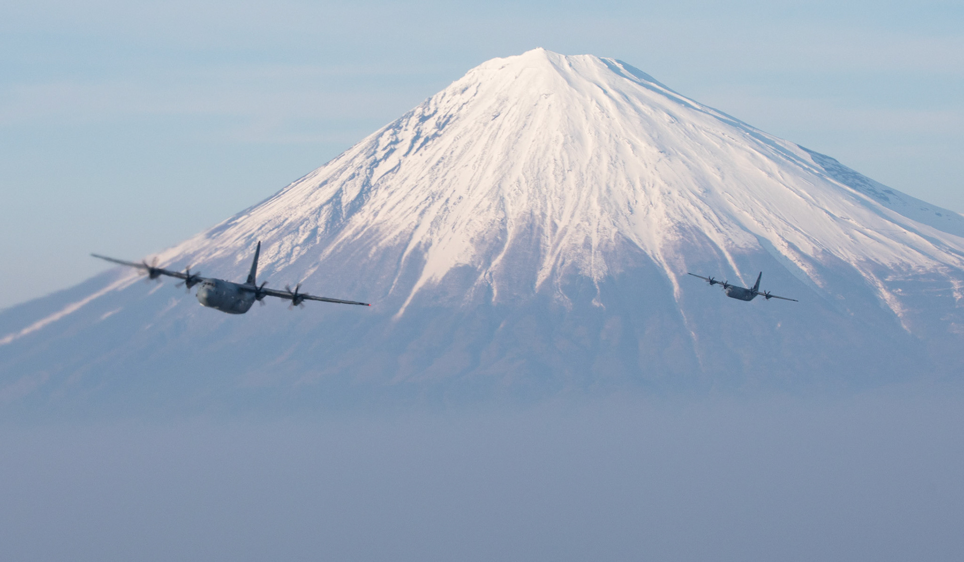 Two Air Force C-130J Super Hercules’ assigned to the 36th Airlift Squadron fly near Mount Fuji, Japan, March 26, 2018. The C-130J provides tactical airlift worldwide. Its flexible design allows it the capability to operate in austere environments. (U.S. Air Force photo by Yasuo Osakabe)