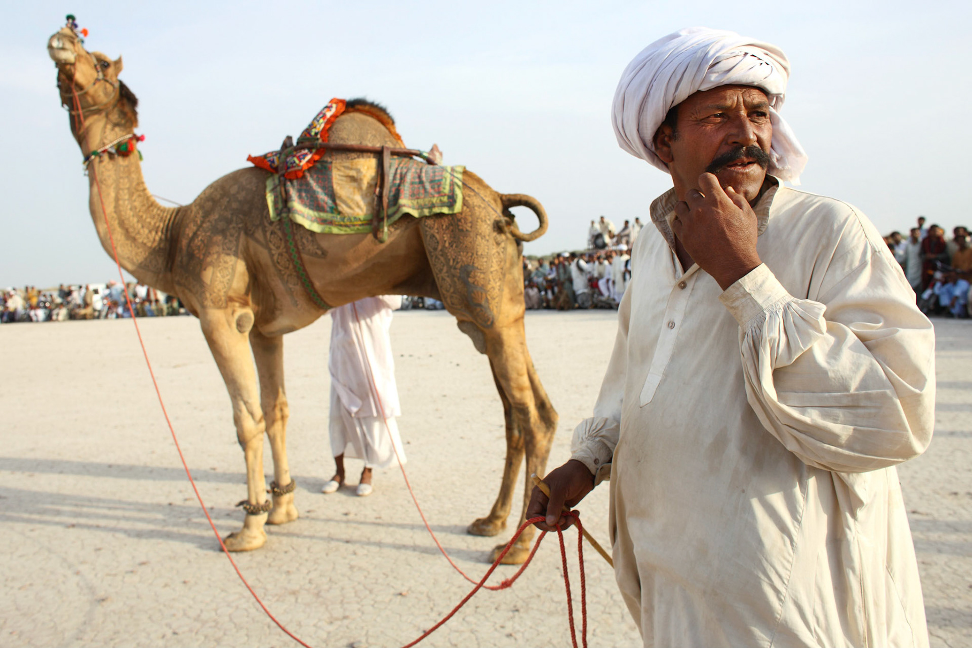 He is the camel trainer. He trains his camel as the acrobatic performance. Also he makes such a beautiful engraved on his camel. (Travel)