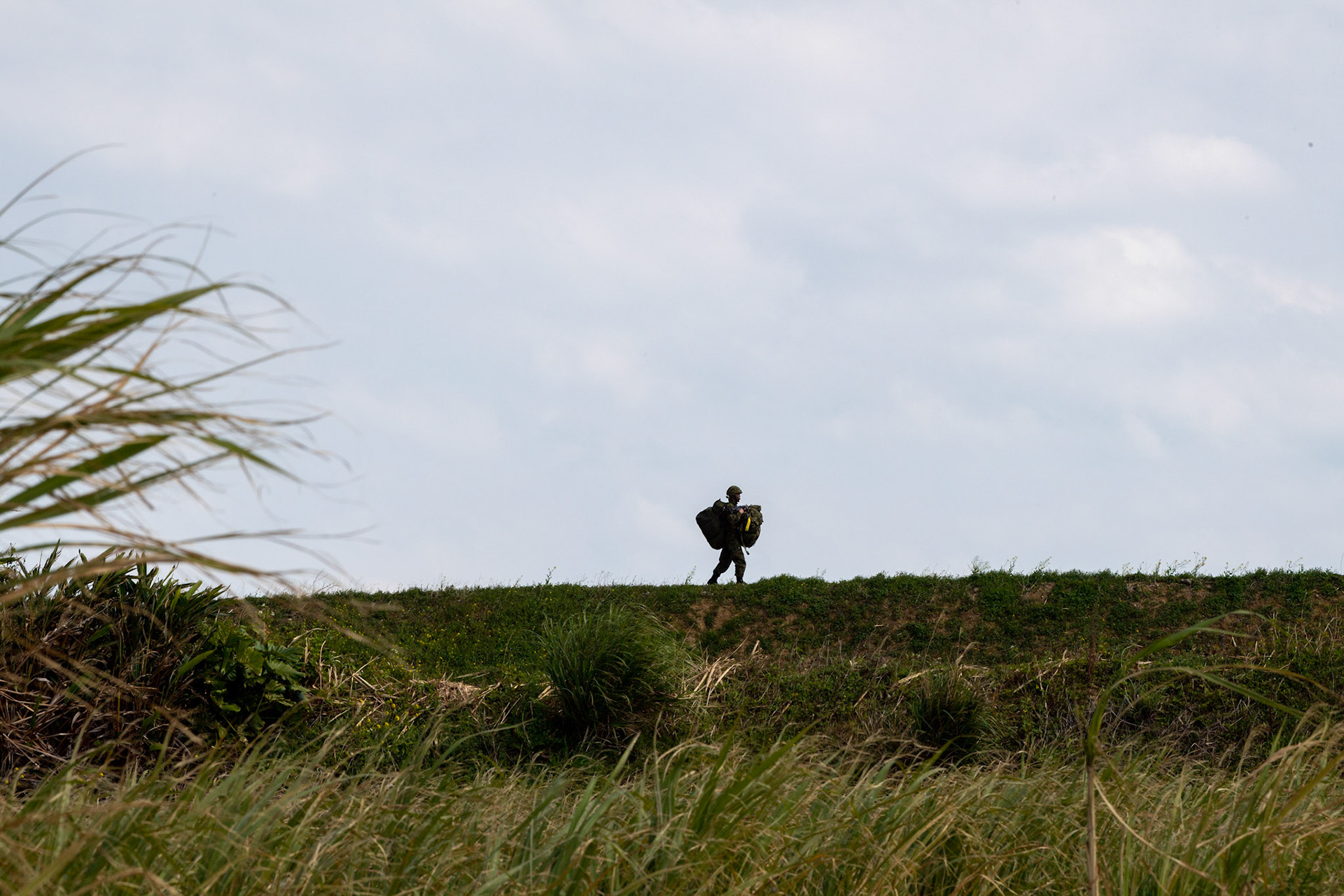 A Japan Ground Self-Defense Force paratrooper assigned to the 1st Airborne Brigade carries his equipment after landing at Kikaijima Island, Japan, March 3, 2023, during Field Training Exercise Iron Fist 23.  During the exercise, the USAF and Japan Self-Defense Forces conducted simulated island seizure airborne operations as the U.S. Marine Corps performed a simultaneous amphibious assault onto the beachhead. (U.S. Air Force photo by Yasuo Osakabe)