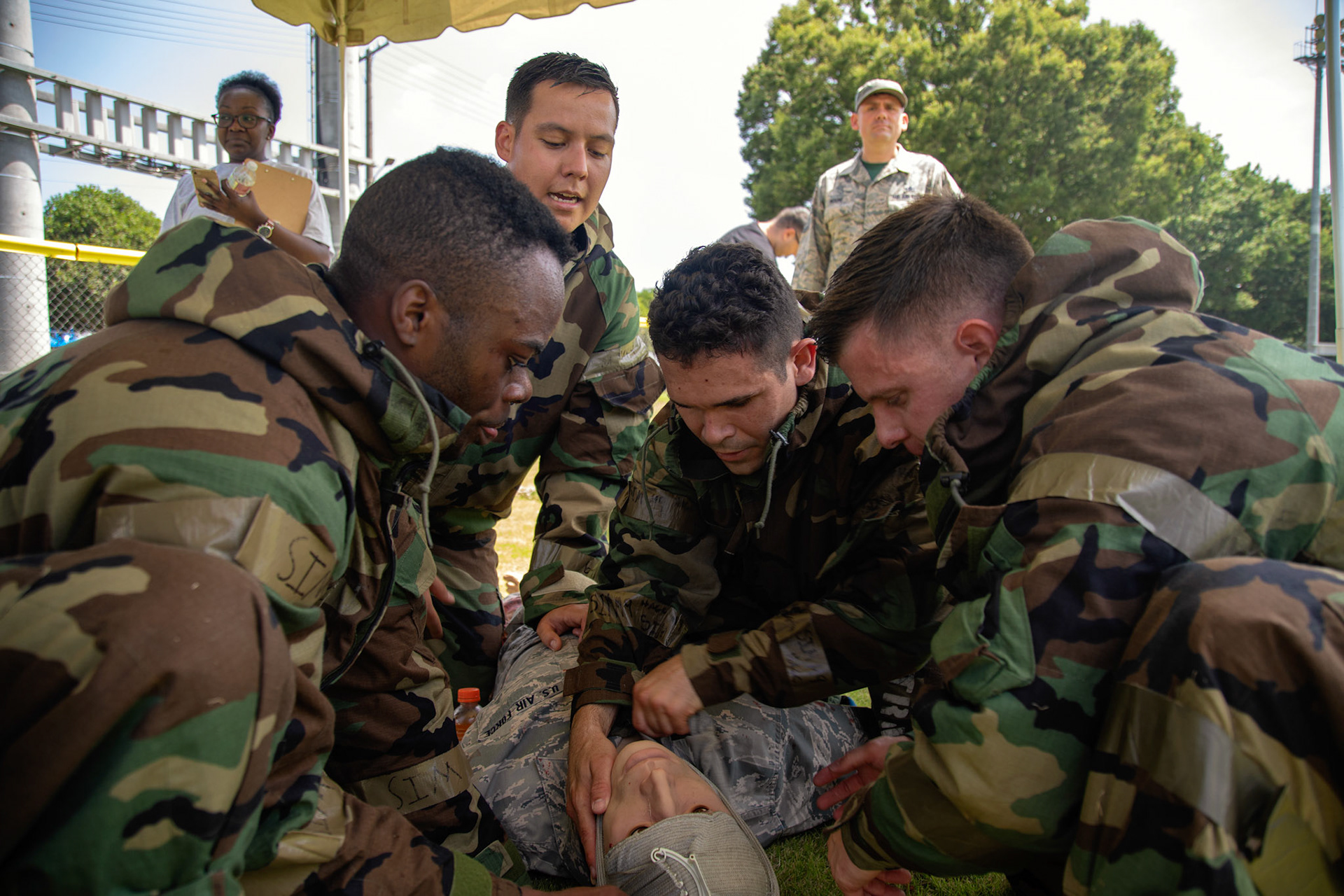 Airmen with the 374th Civil Engineer Squadron perform a self-aid and buddy care during an Ability to Survive and Operate (ATSO) Rodeo at Yokota Air Base, Japan, June 8, 2018. The rodeo involved participants wearing different stages of mission-oriented protective posture (MOPP) gear after pushing a Hunvee and going through various areas of training including self-aid and buddy care, post-attack reconnaissance, four-person relay, and "shoot, move and communicate." (U.S. Air Force photo by Yasuo Osakabe)