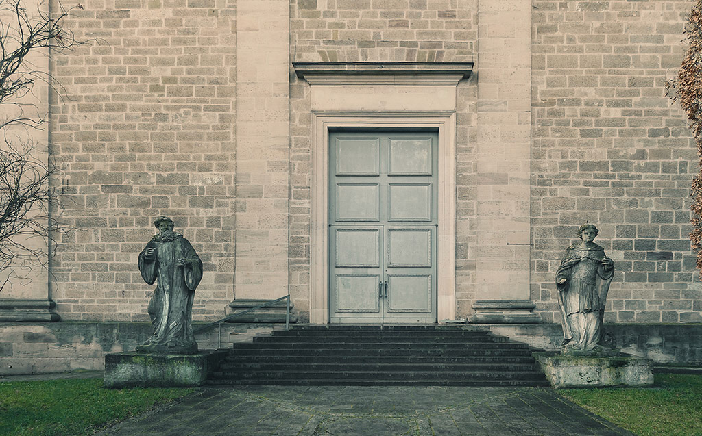 Two very old gatekeeper figures in front of an ancient door. They shall protect this church from incoming evil.