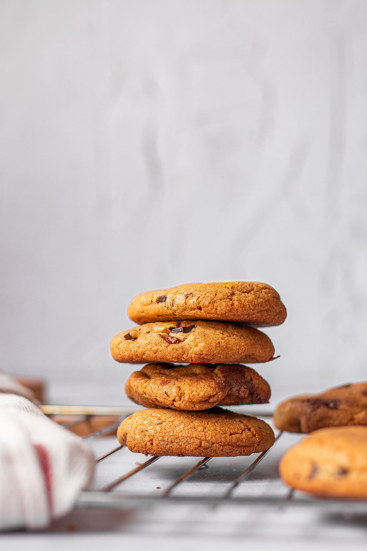 Stack of golden cookies cooling on a metal rack against pale blue