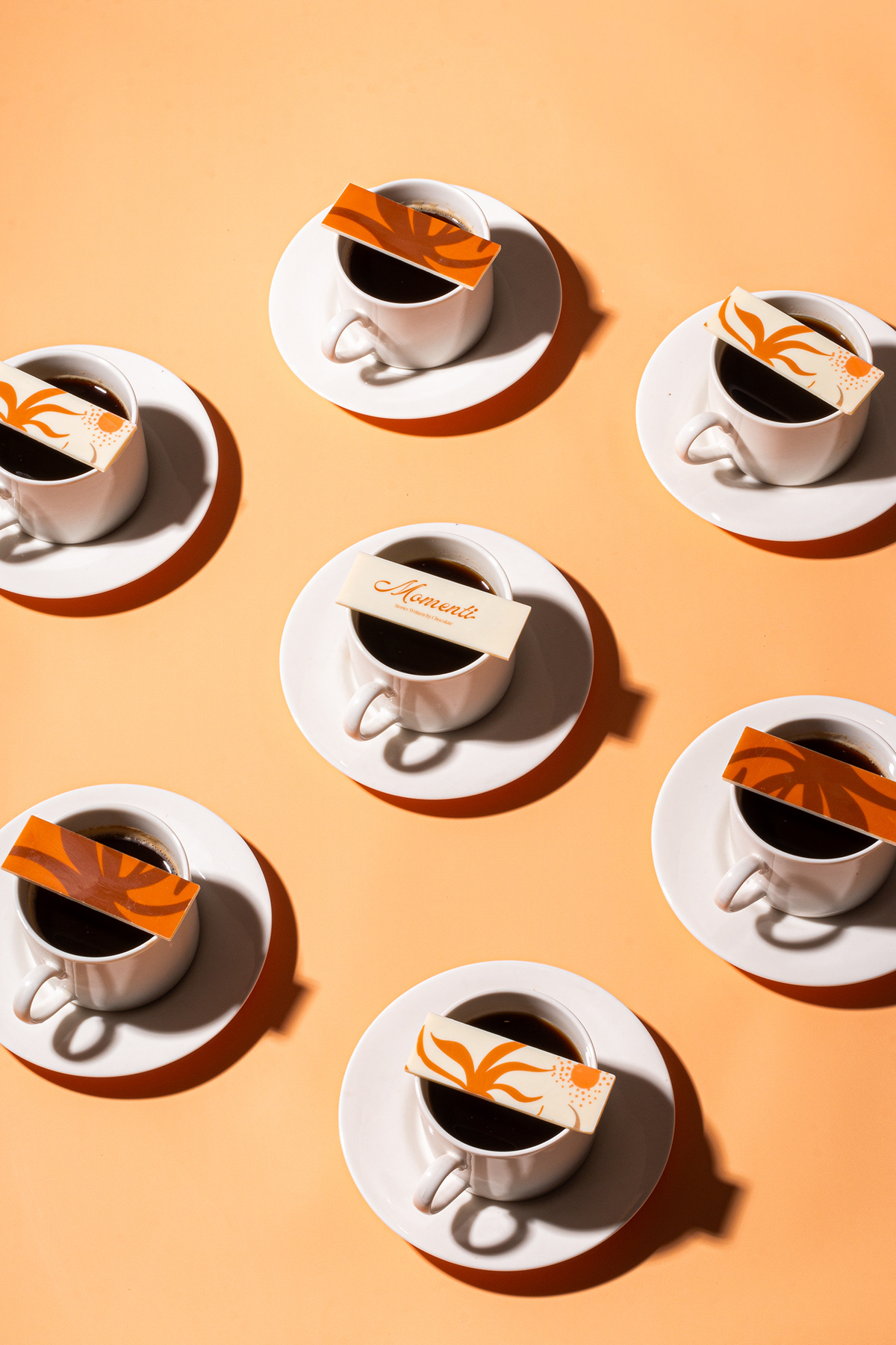 Overhead arrangement of coffee cups casting long shadows on orange