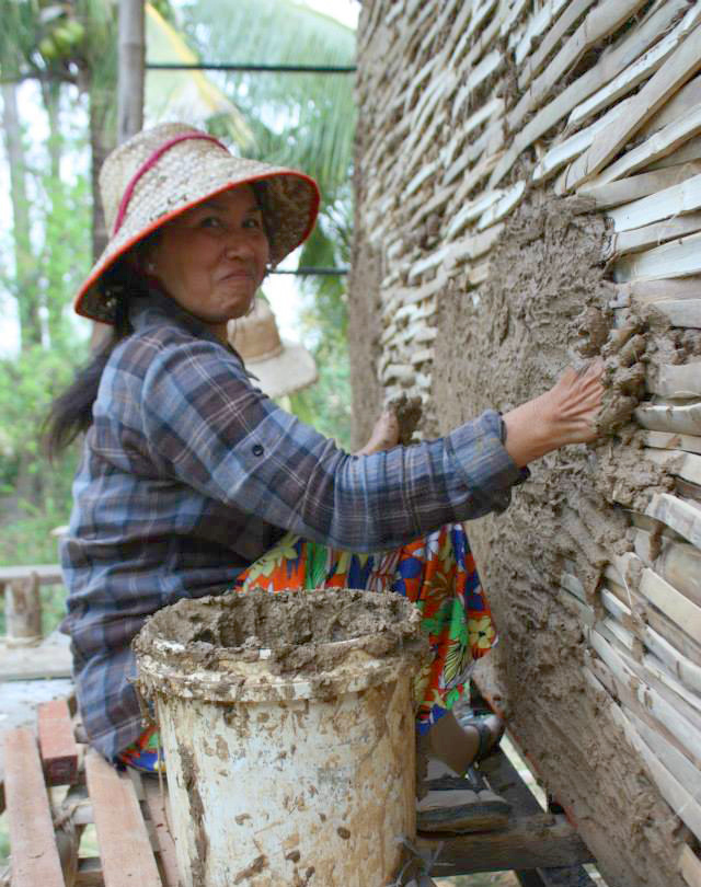 A TEACHER HELPING WITH THE WATTLE AND DAUB WALL