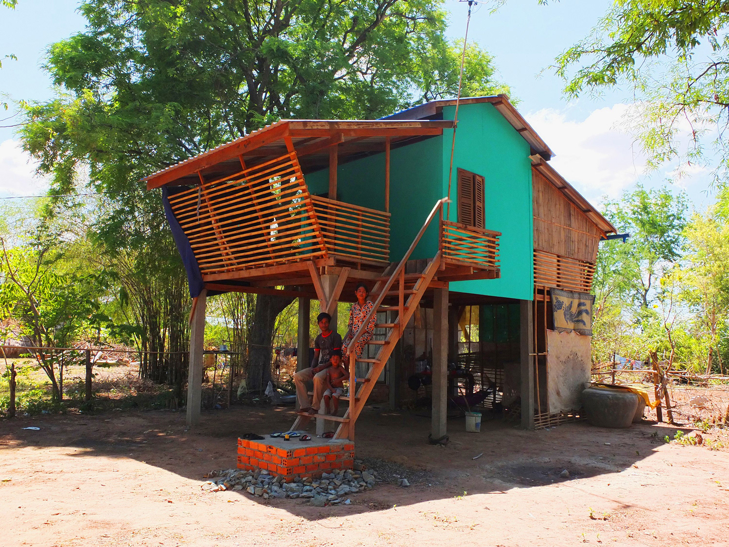 PICTURE OF ONE OF THE COMPLETED HOUSES WITH THE OWNERS SITTING ON THE STAIRS