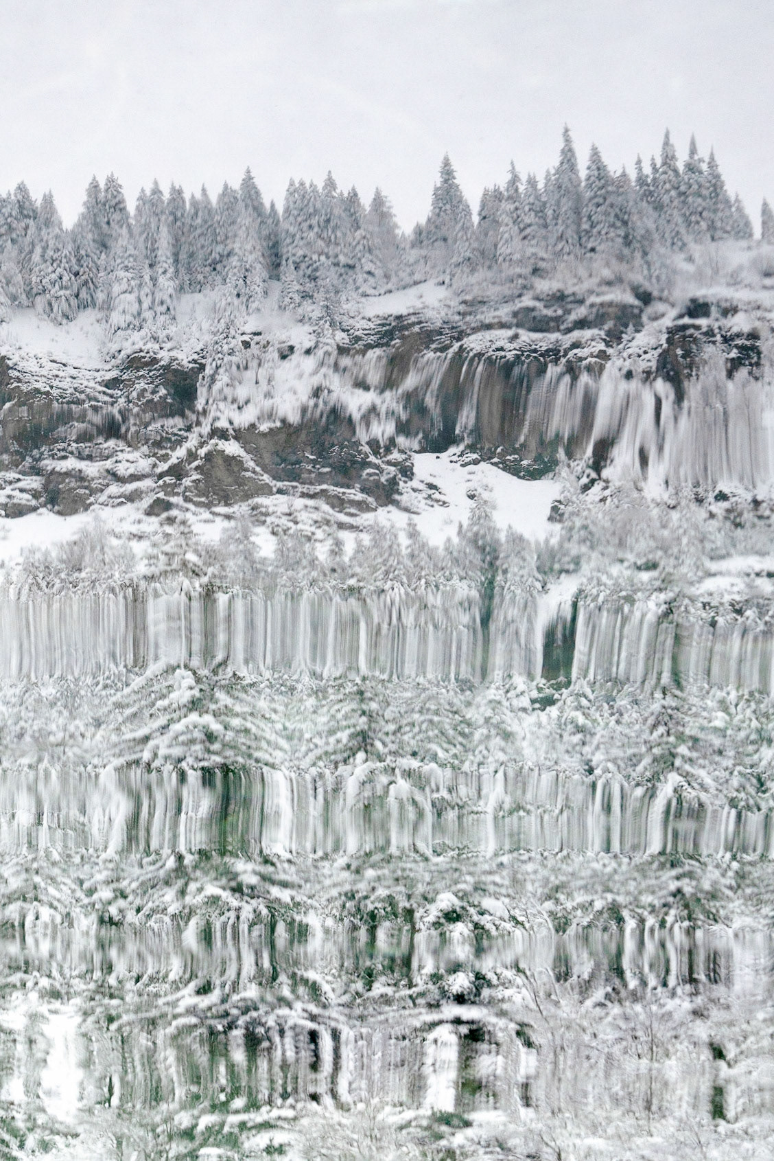 Reflet de sapins enrobés de neige, rocher en tranche épaisse, ondulations étirantes