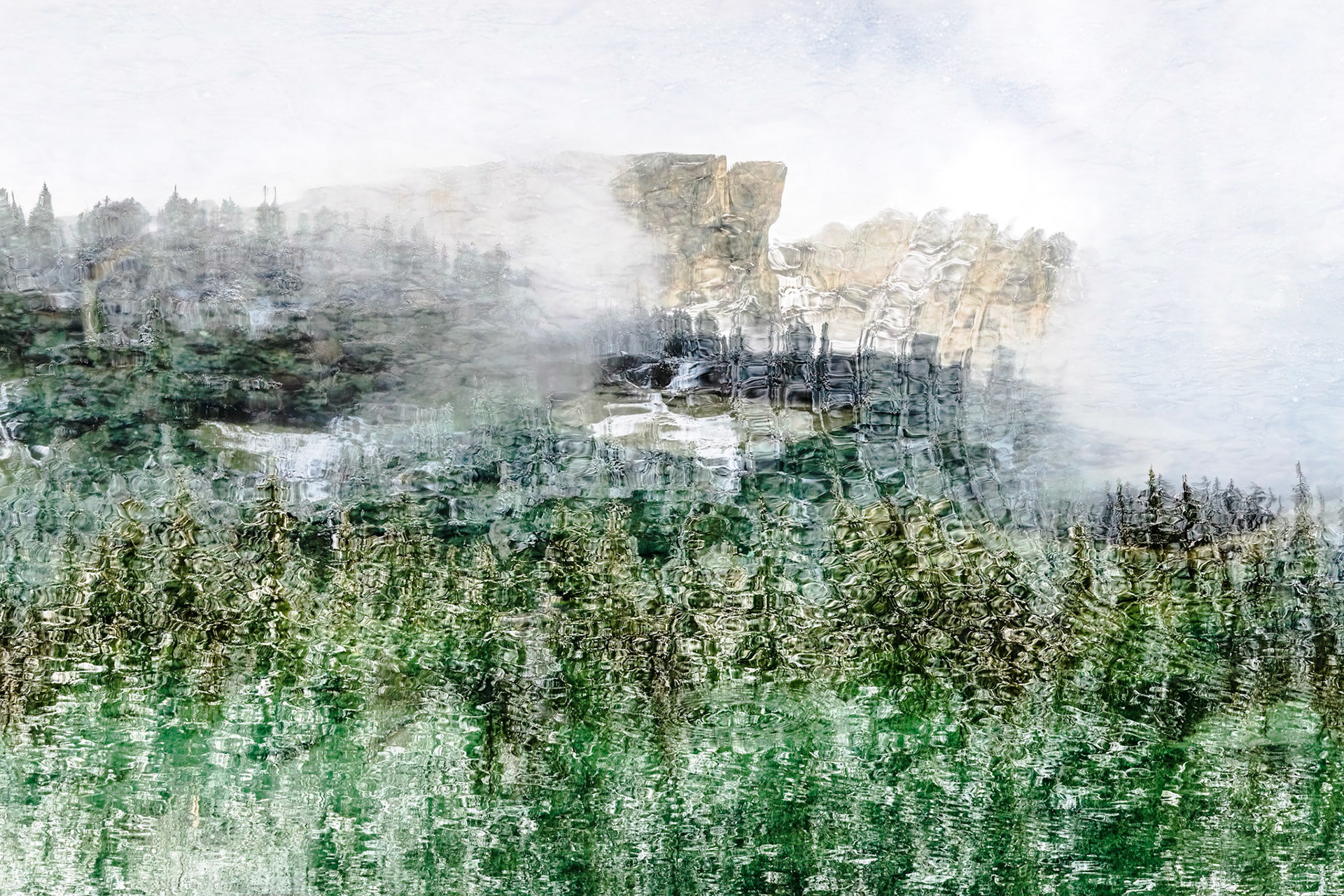 Reflet de sommets brumeux et sapins poudrés, perturbé de vagues concentriques, variations de noir et de verts naturels