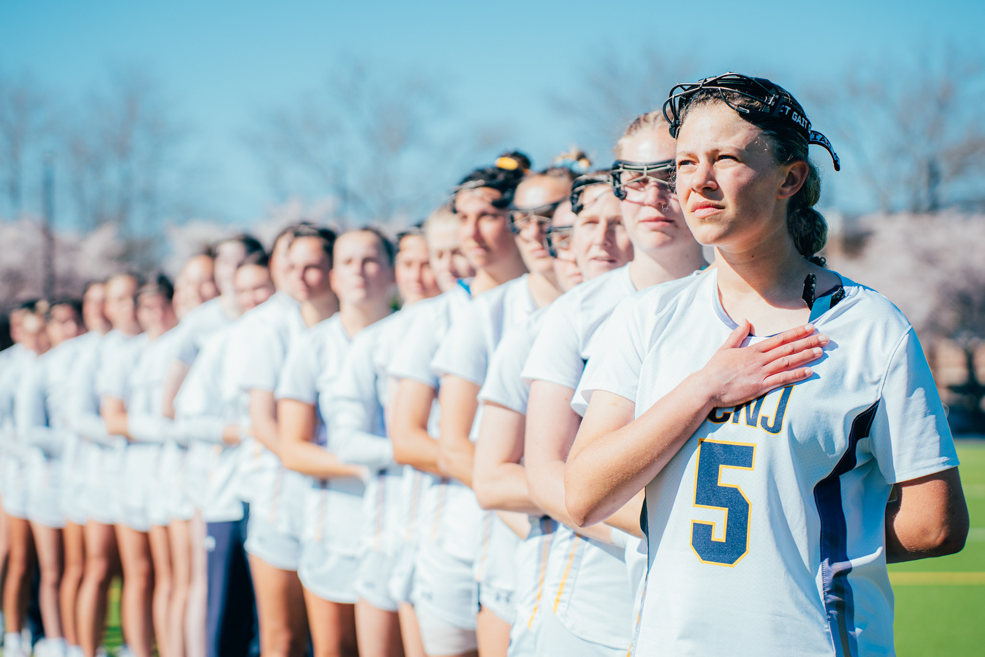 The College of New Jersey lacrosse team lines up during the national anthem before a game against Kean University at TCNJ Field Hockey and Lacrosse Complex in Ewing, N.J., on Apr. 9, 2025.