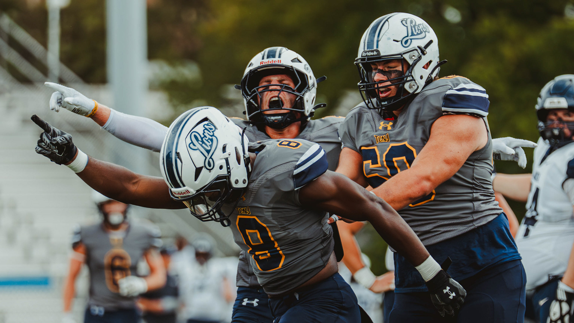The College of New Jersey defensive backs Christian Bennett (8), Justin Kurc (7) and defensive lineman John Russo (50) celebrate a fourth-down turnover against Kean University in Ewing, N.J., on Oct. 25, 2025.