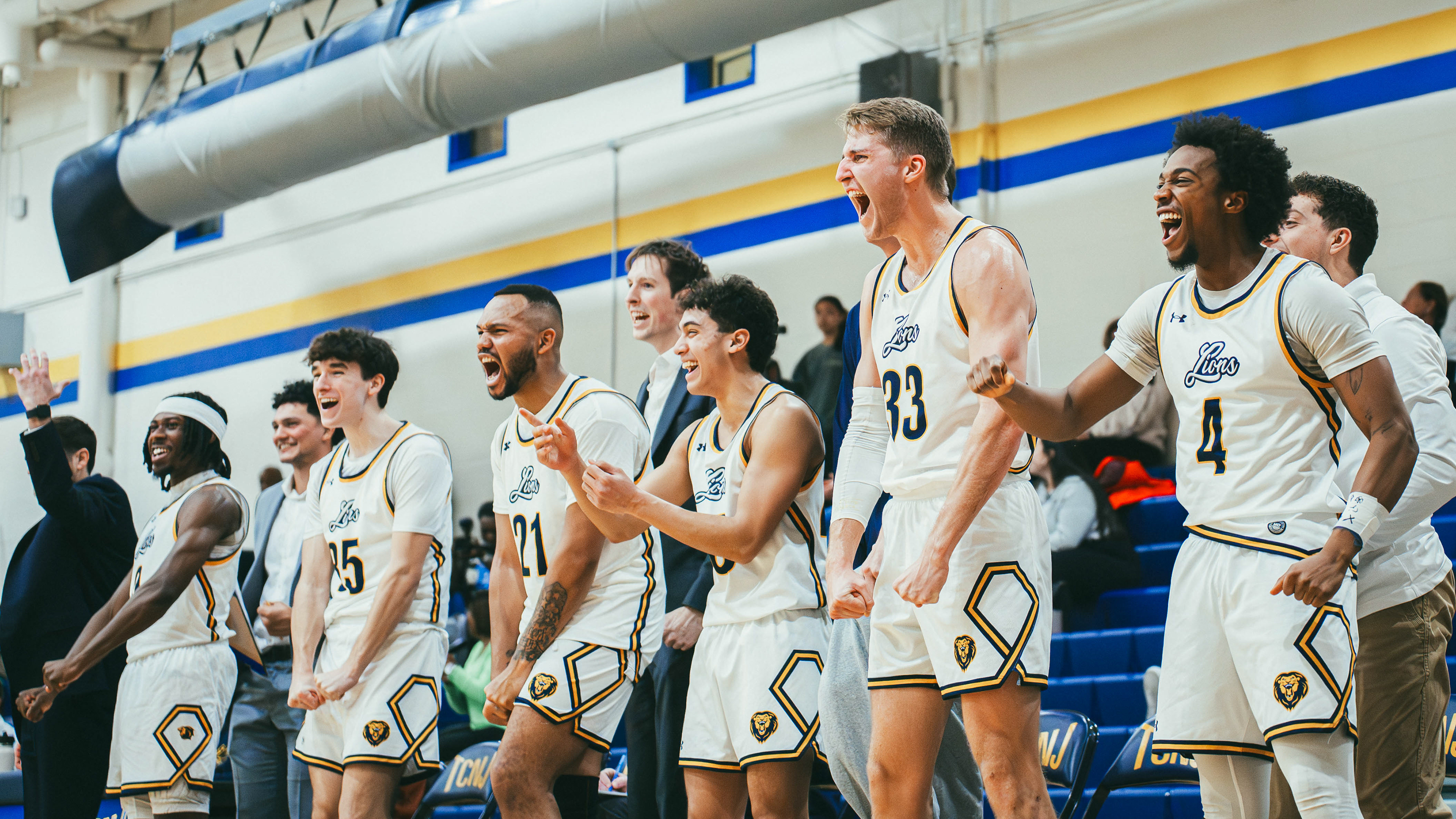 The College of New Jersey guard Jordan Robinson (0), guard Mason Mangione (35), guard Anthony Milligan (25), guard Lucas Dipasupil (20), forward Matthew Solomon (33), and guard Connor Howard celebrate after a three-point basket gives them the lead against Rutgers-Newark at Packer Hall in Ewing, N.J., on Jan. 10, 2026.