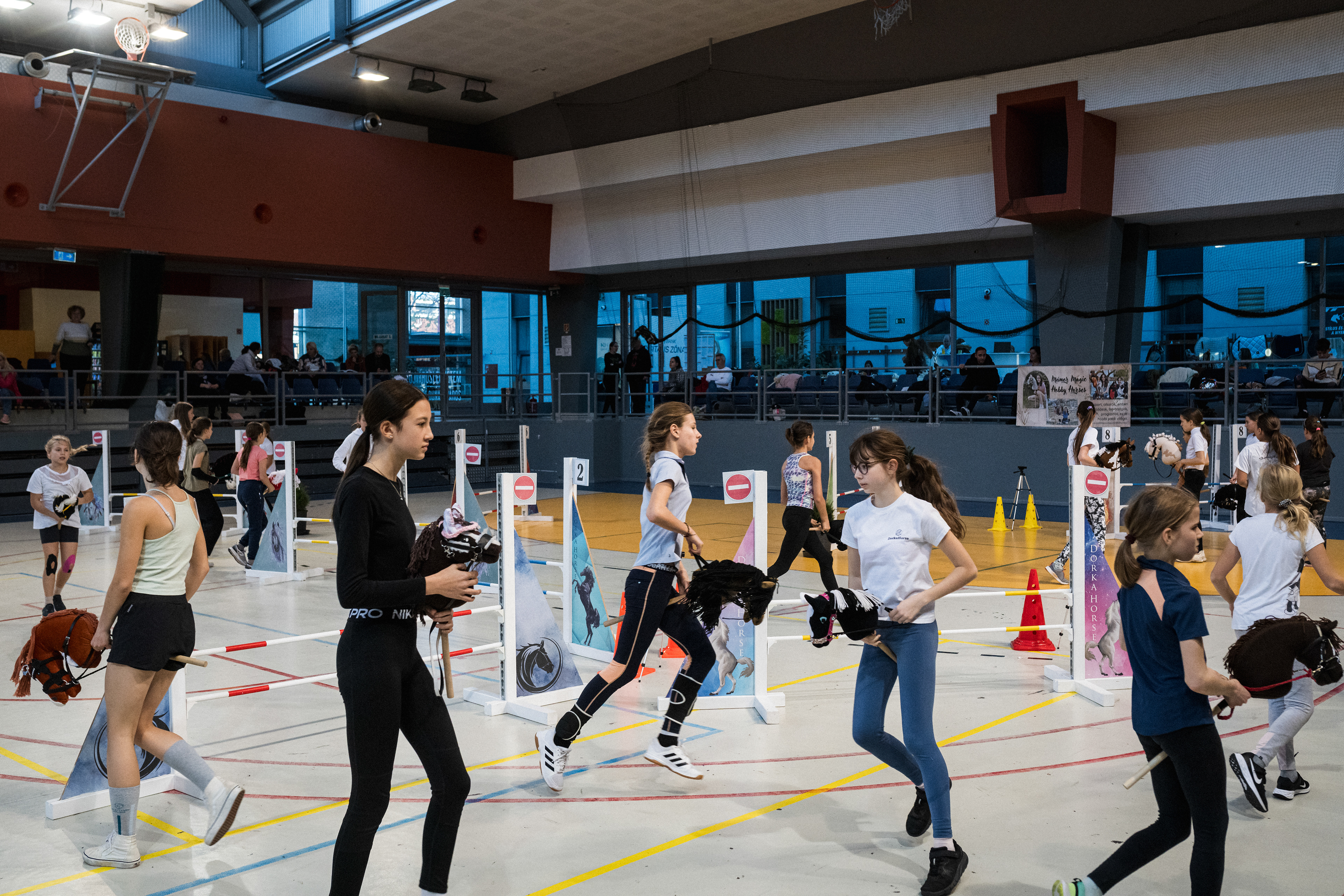 Participants warm-up and practice the tracks before the race events at the End of the Year Cup hobby horsing competition in Dunaújváros  Finland is the cradle of the modern hobby horse, and the sport was born in the second half of the 2010s. There are two main categories of competition, dressage and show jumping. In the first, the competitors have to perform a choreography imitating the movement of the horse, with compulsory elements in sync with the hobby horse, but beyond that the performance is limited only by the imagination. In the second case, the riders have to jump over obstacles of different heights and run through the course in the correct order, with the hobby horse between their legs. The sport takes almost all its inspiration from 'real' equestrian sport, with the difference that instead of a live horse, the competitors use a hobby horse. (The growing popularity of the sport is reflected in the recent formation of the International Hobby Horse Federation (IHHF).) 
