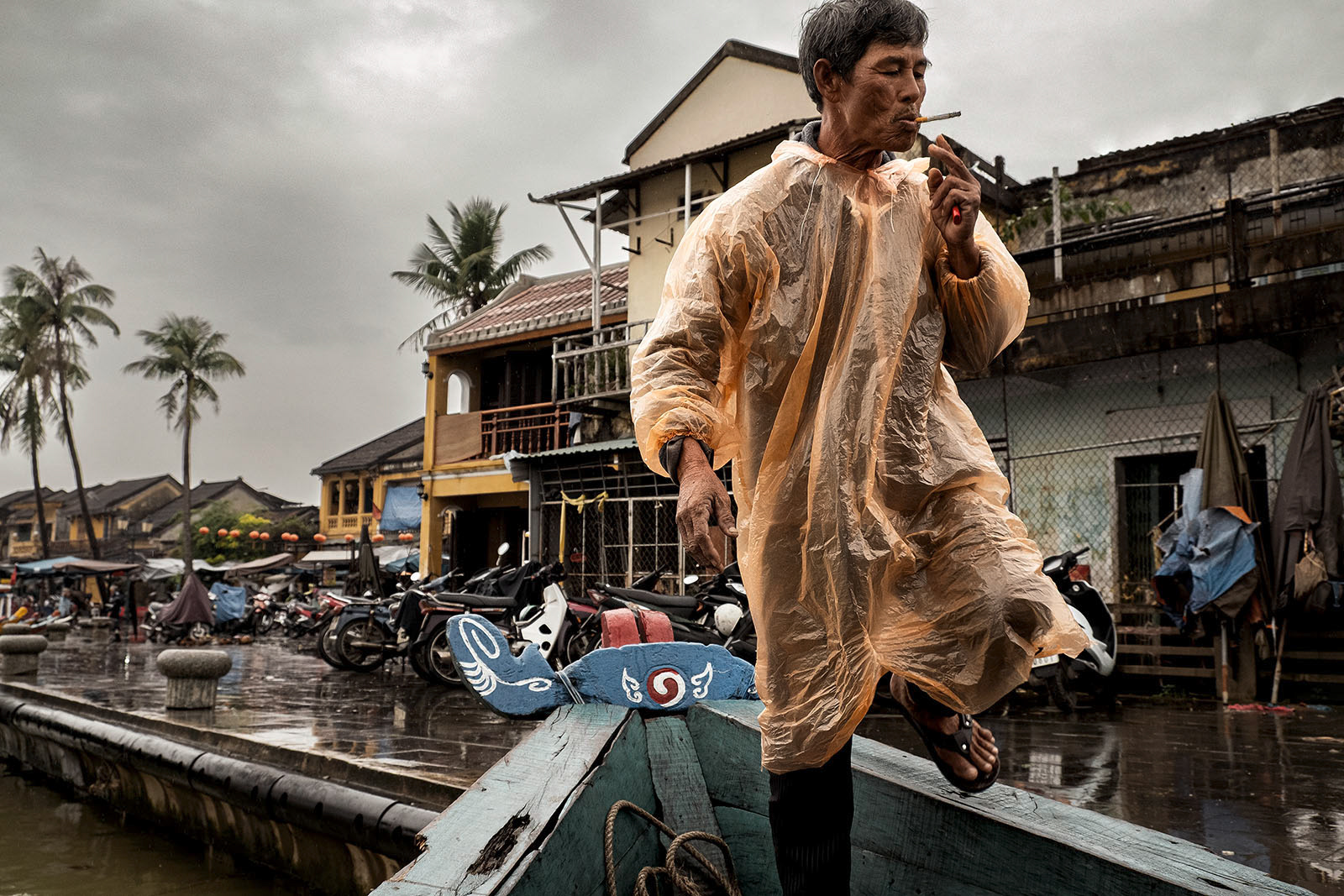 Flo Payer – Reportagefotografie in Vietnam, Hoi An: Mann im Regenponcho steigt in ein Boot