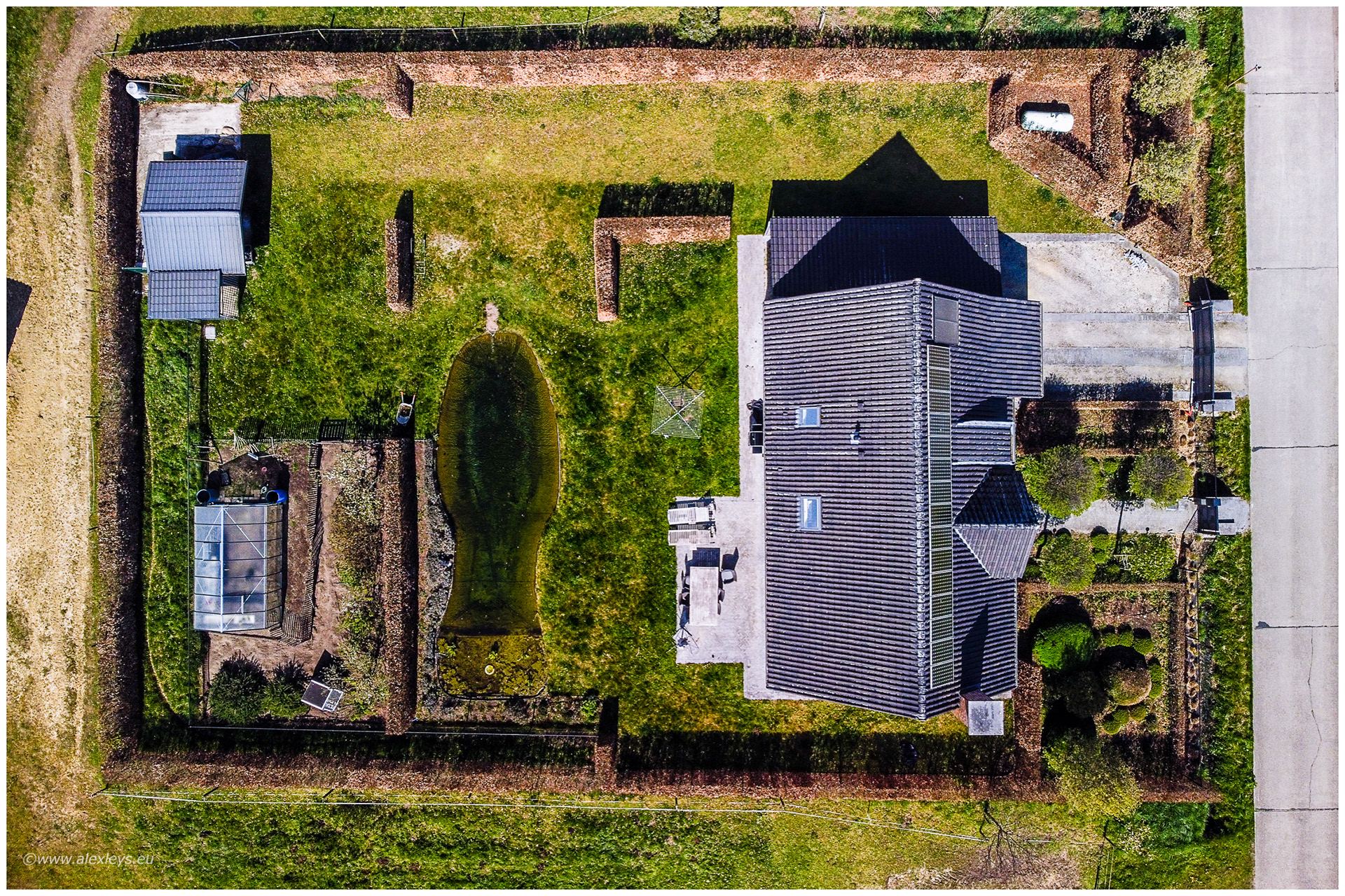 Luchtfoto van een woning met zwemvijver en aangelegde tuin