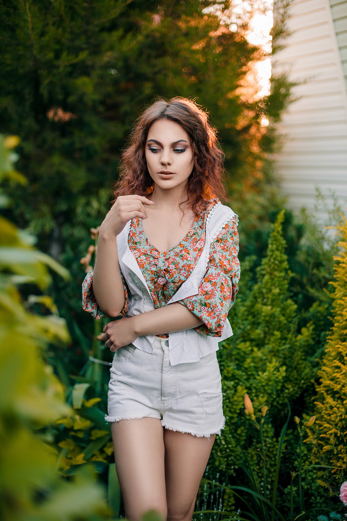 Beautiful young woman in romantic styled white shorts, blouse and vest on foliage background. Perfectly retouched.