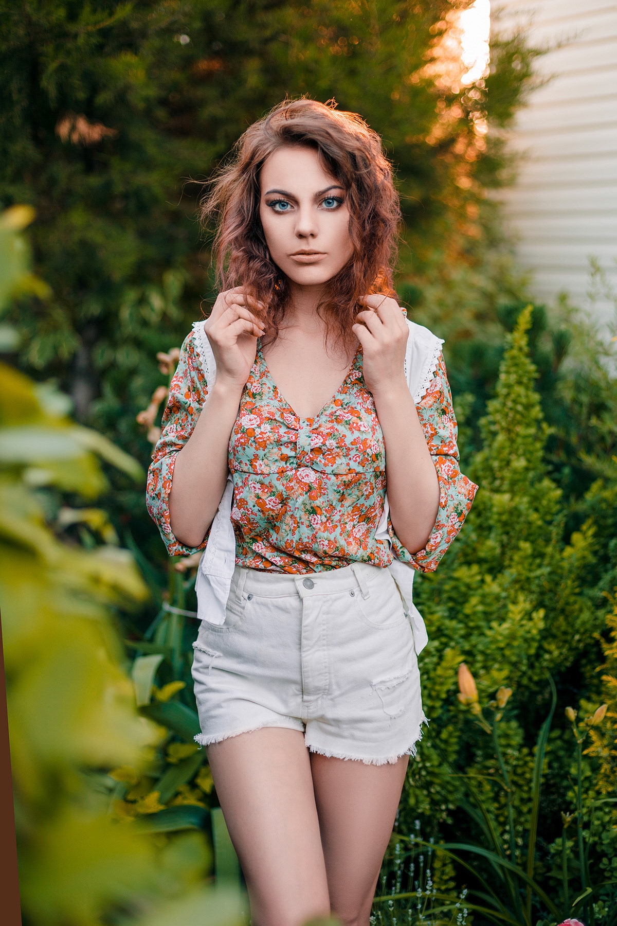 Beautiful young woman in romantic styled white shorts, blouse and vest on foliage background. Perfectly retouched.