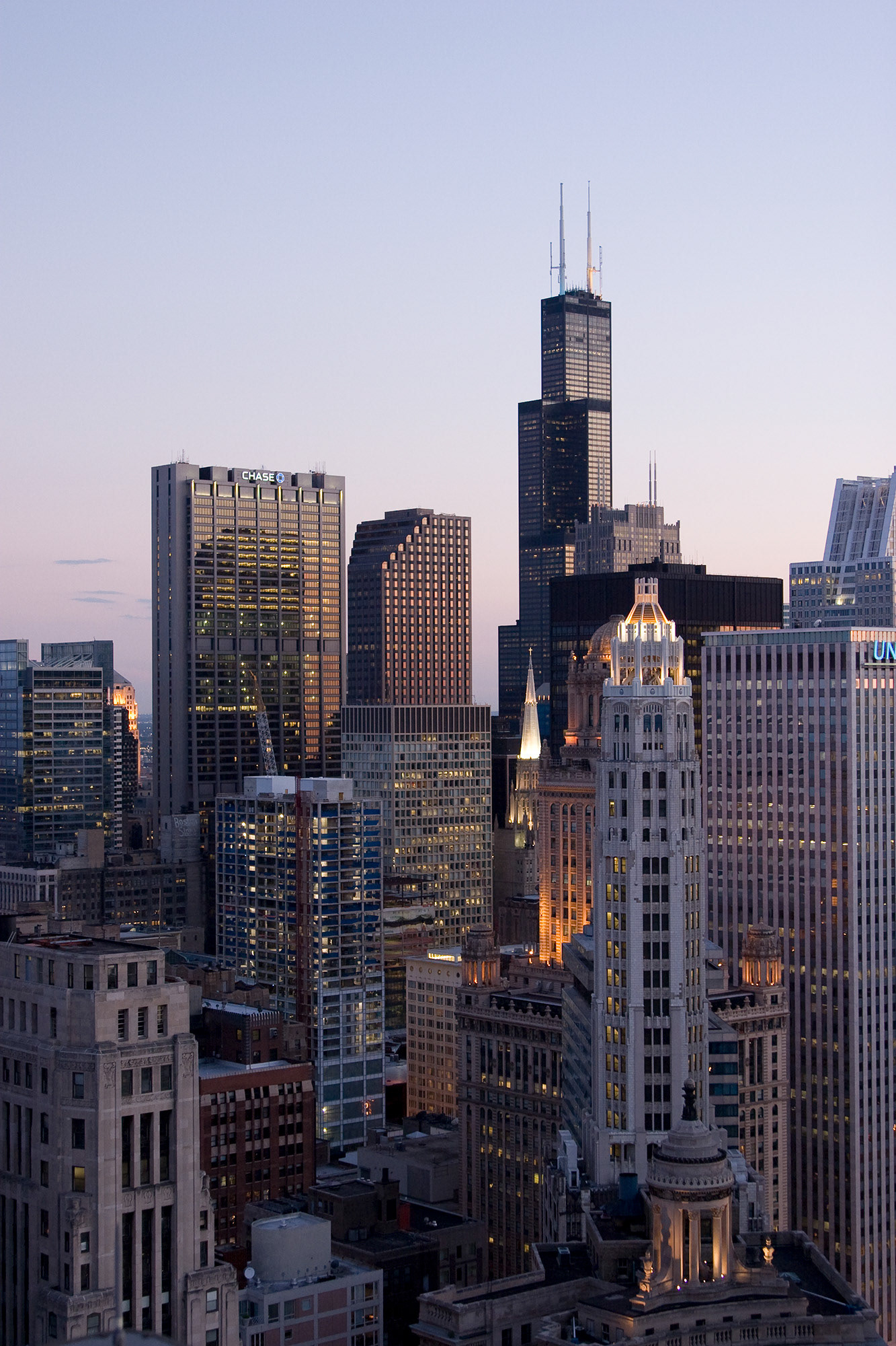 The chicago skyline at dusk taken from a tall building rooftop looking south towards the Willis Tower