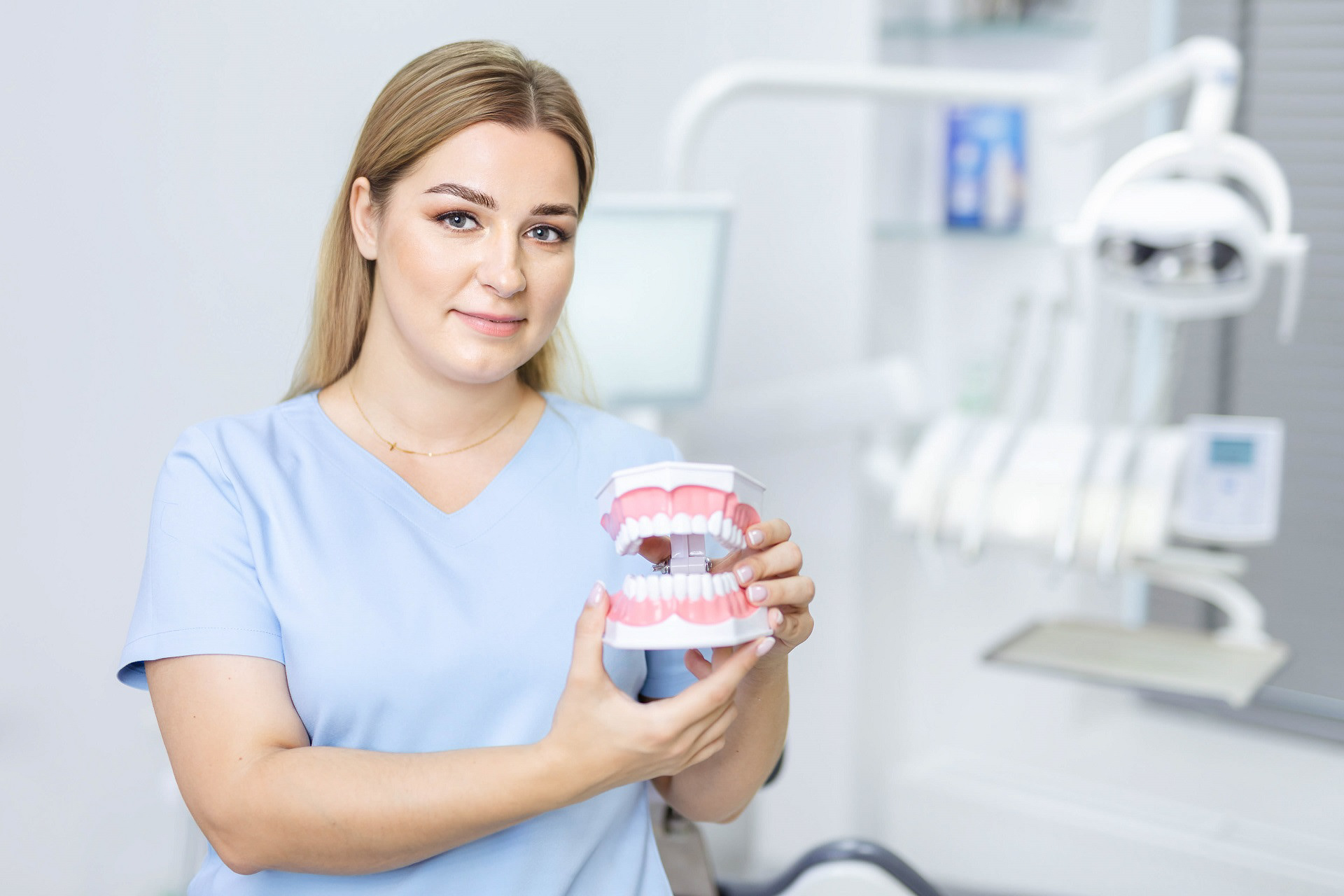 pani dentystka w gabinecie stomatologicznym trzyma pokazowe uzębienie człowieka