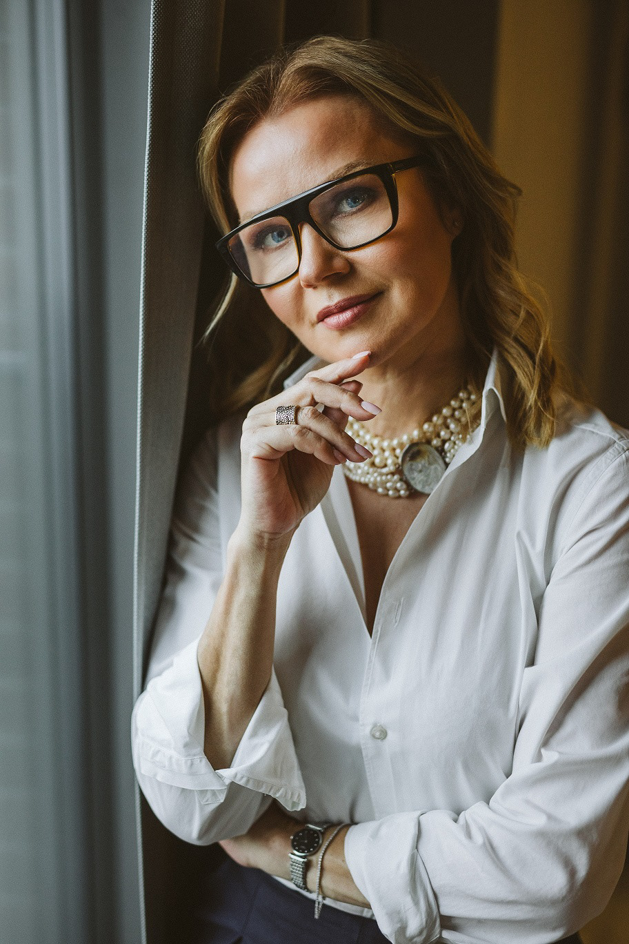 Portret Pani Dyrektor Białostockiego Centrum Onkologicznego w czarnych okularach stojąca przy oknie