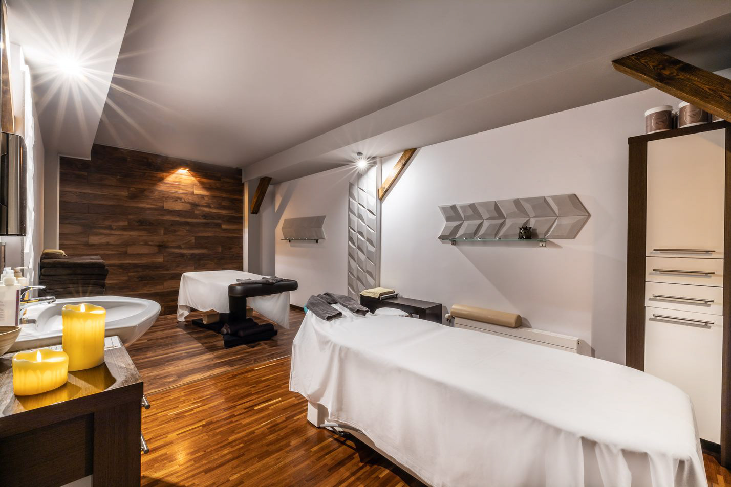 Hotelowa strefa relaksu z dwoma łóżkami zabiegowymi, świecami i eleganckim wystrojem