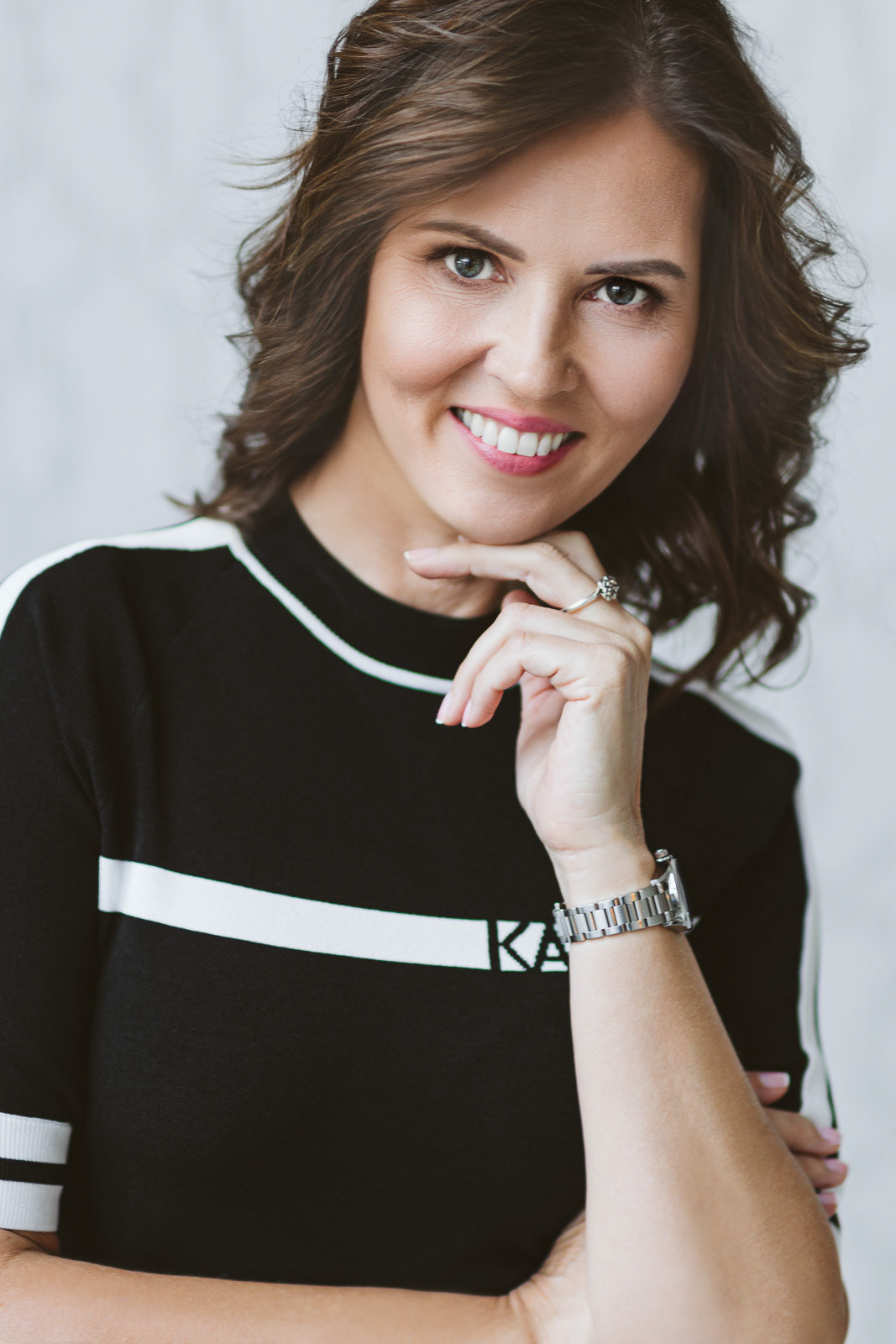 piękna kobieta o ciemnych włosach patrzy prosto w obiektyw z ładnym uśmiechem i podpiera się ręką
