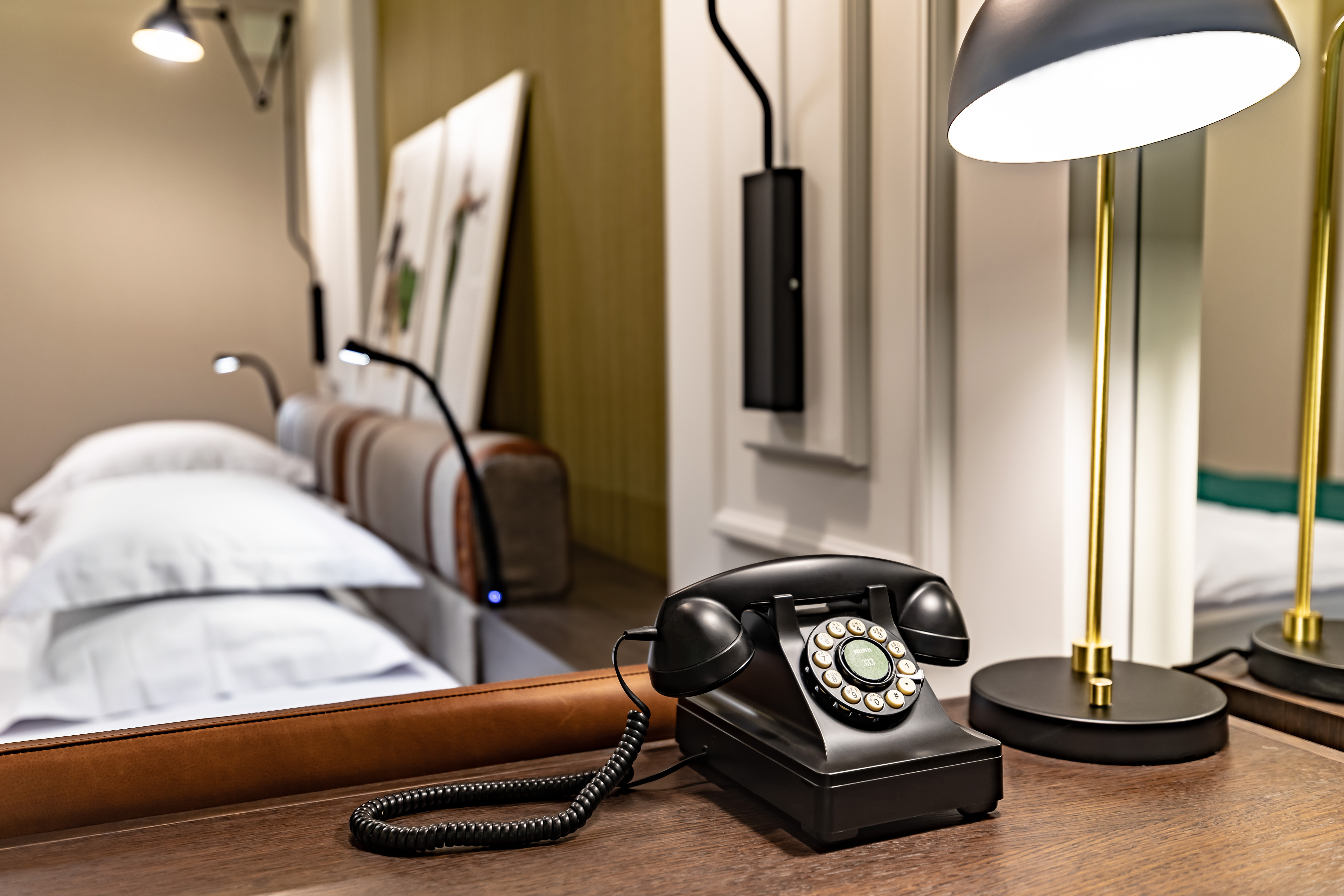 replika starodawnego telefonu na biurku obok lampki w pkoju hotelowym