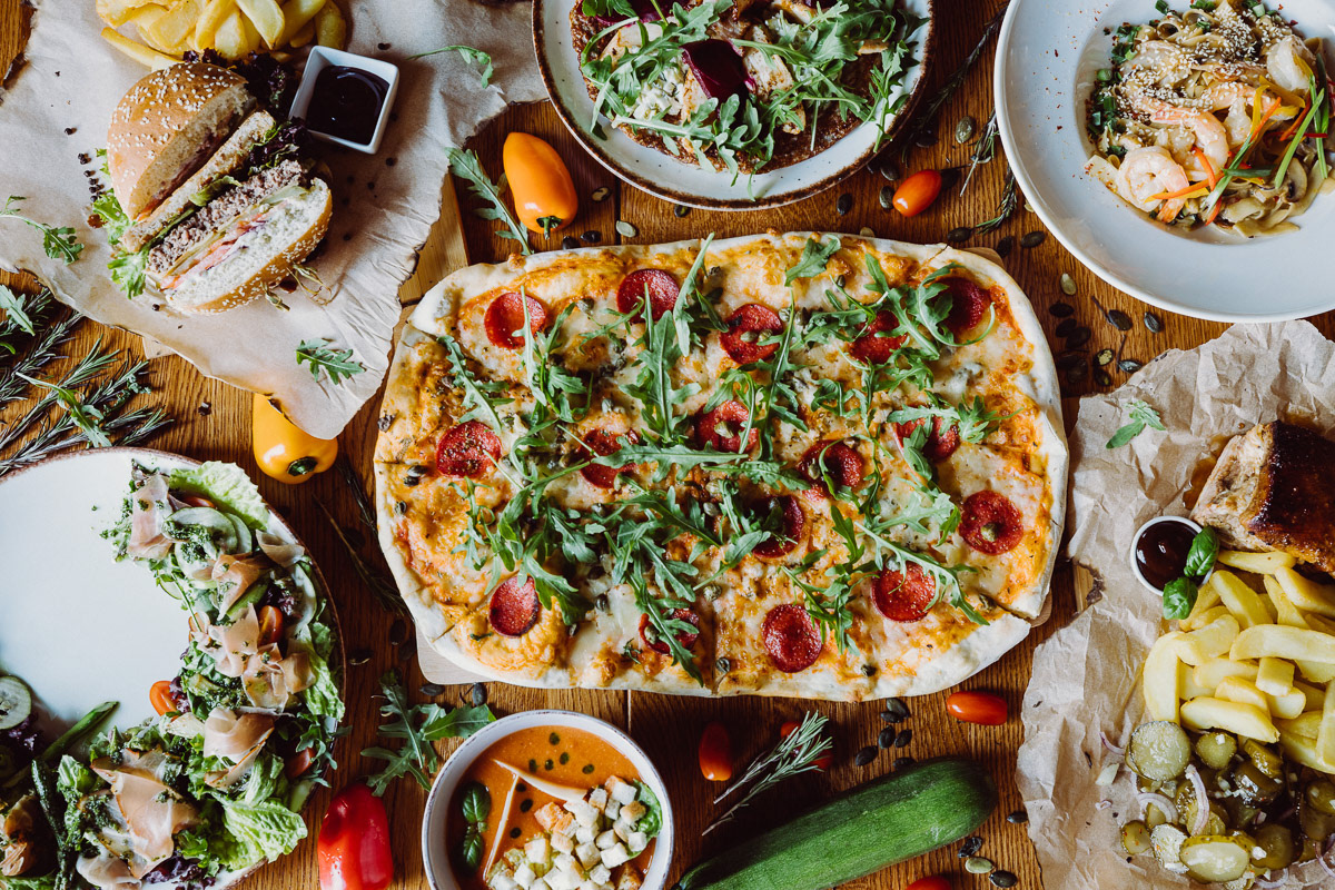 pizza z salami na drewnianym stole otoczone innymi potrawami w restauracji