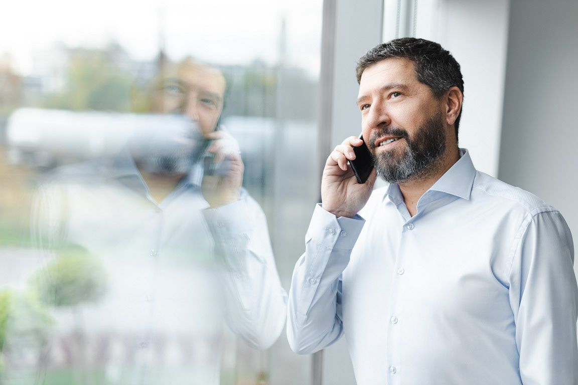 prezes dużej firmy rozmawia przez telefon zerkając przez okno