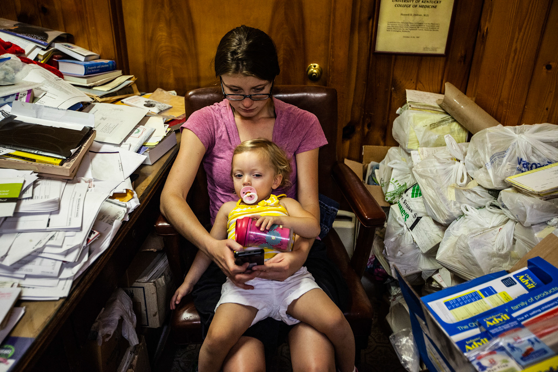 Bethany Selby, 22, holds her daughter Ava Selby, age 18 months, as she waits in the doctor’s cluttered office.