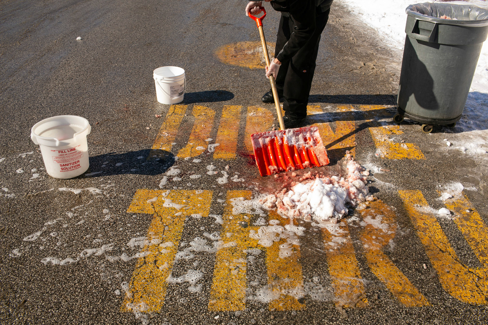 A McDonalds employee washes away a blood stain from the parking lot where 17-year-old boy was shot and killed. (Chicago Tribune)