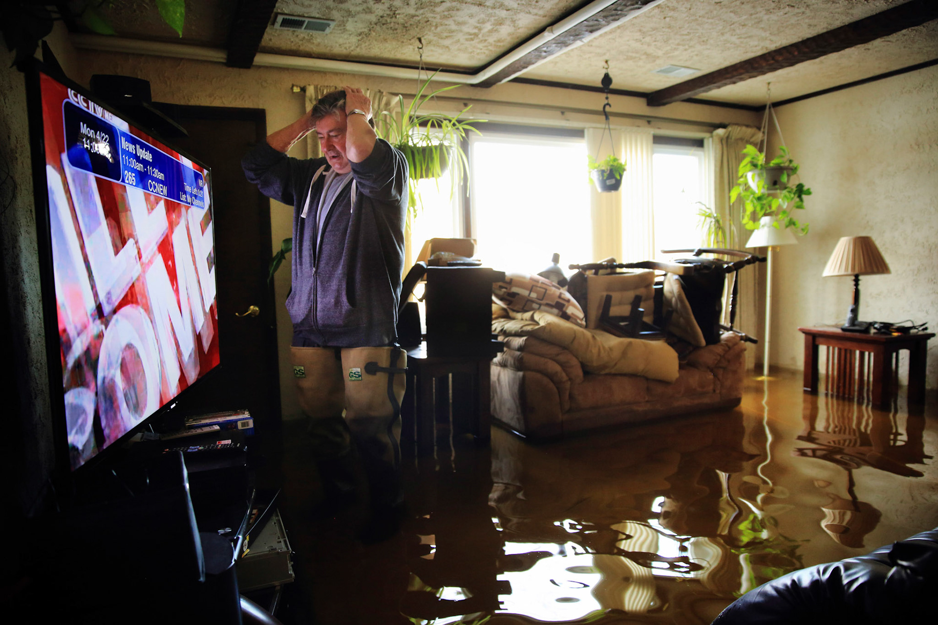 Ron Madon, 74, turns on the news in his flooded home in Fox Lake, Illinois. (ChicagoTribune)