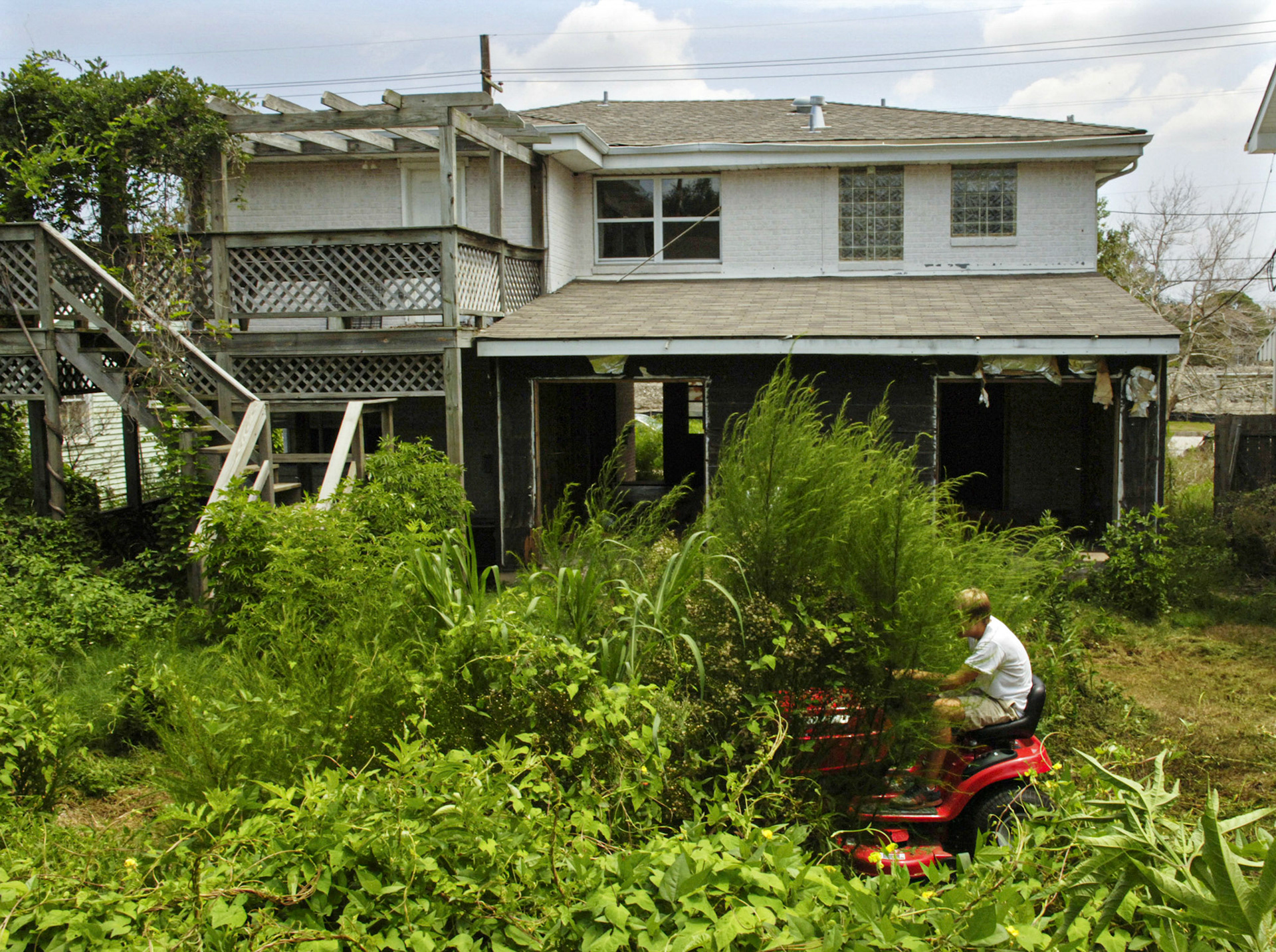 William Stoudt, 17, uses a riding lawnmower to clear an overgrown back yard of weeds Wednesday, August 16, 2006 in his Lakeview neighborhood of New Orleans.