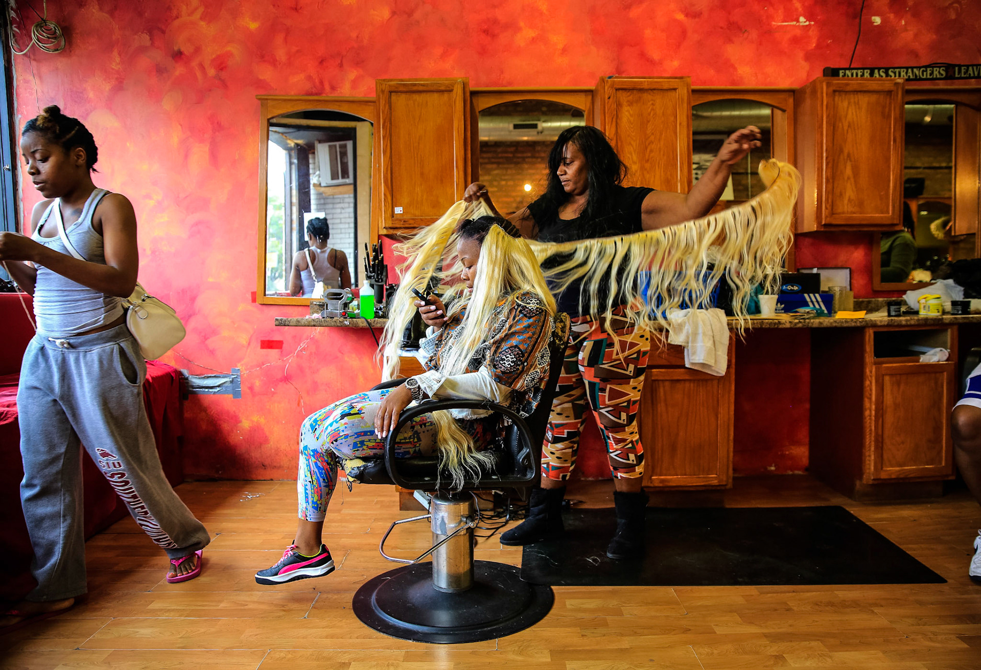 Shardell Washington, 40, standing at right, sews in extensions at her hair salon on California Avenue.