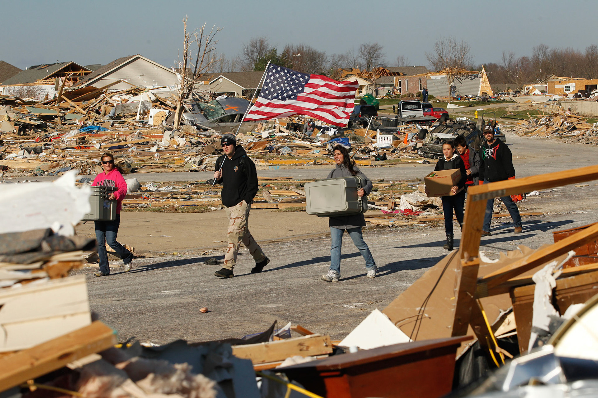 Jake Coyle carries a flag with volunteers arriving to help friends dig out in the wake of a devastating tornado that struck Washington, Illinois. (ChicagoTribune)