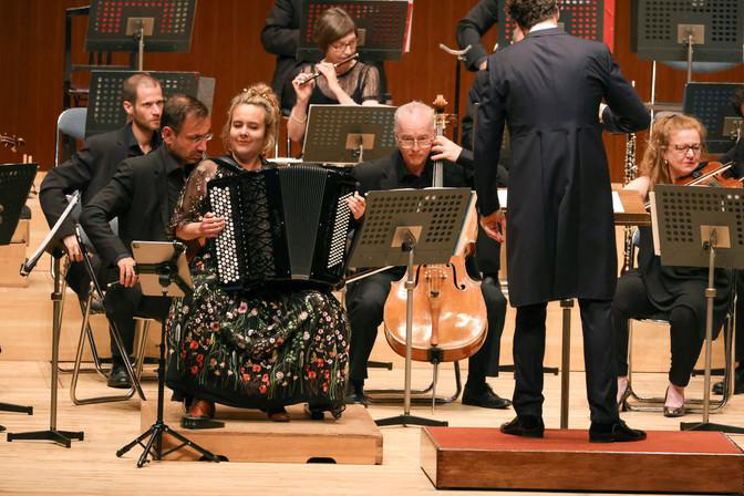 Massgeschneidertes Konzertkleid: Schwarzer Feintüll mit bunten Blumen und transparenten Stickerei-Ärmeln.