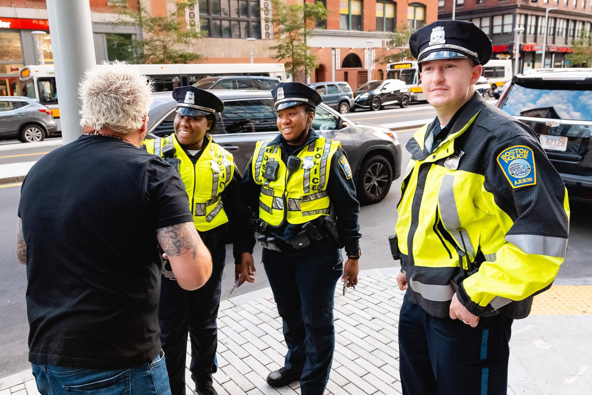 Guy Fieri speaking with local police outside of his newest Boston restaurant location filling them in on what to expect