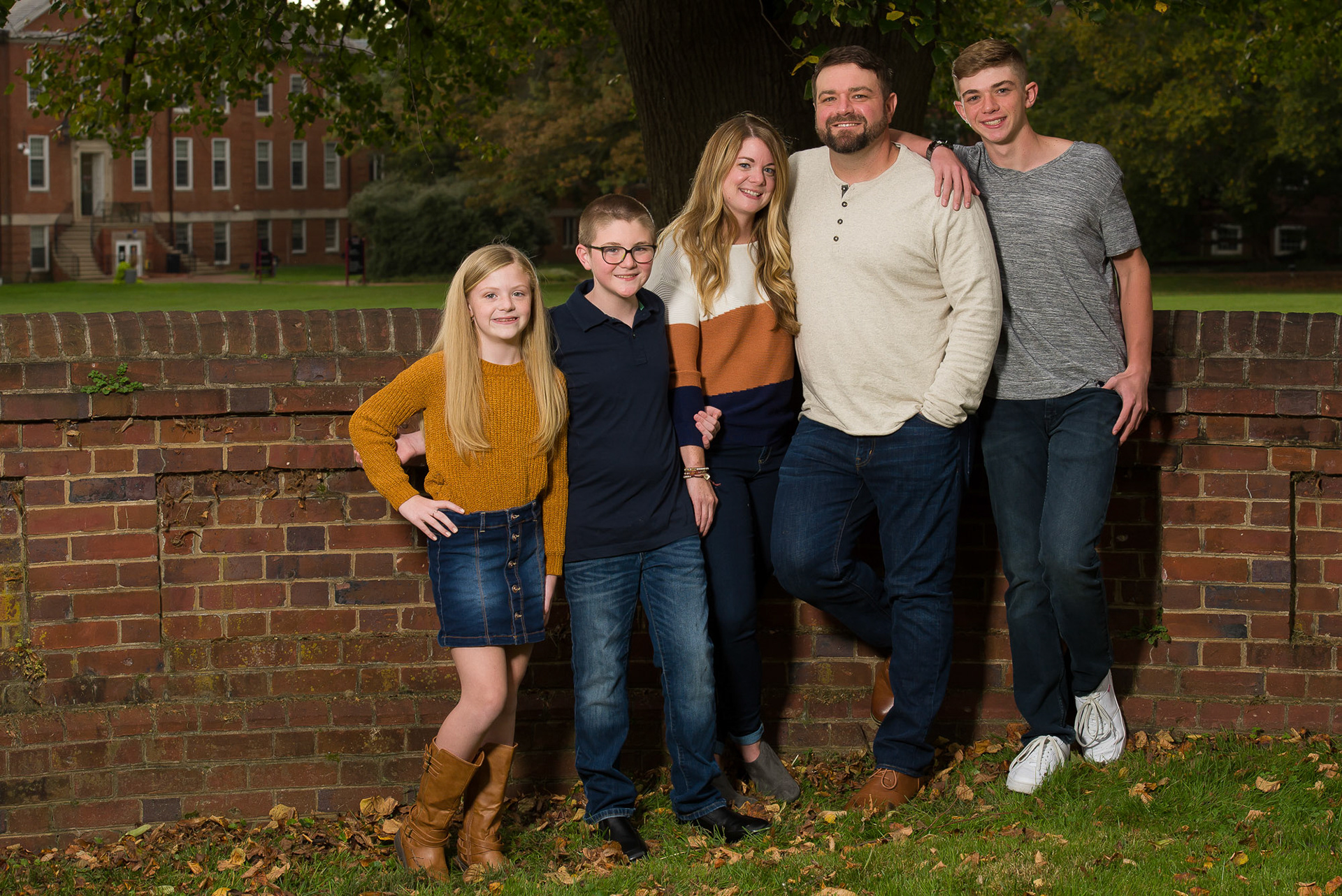 Family photo in a park at a brick wall with College