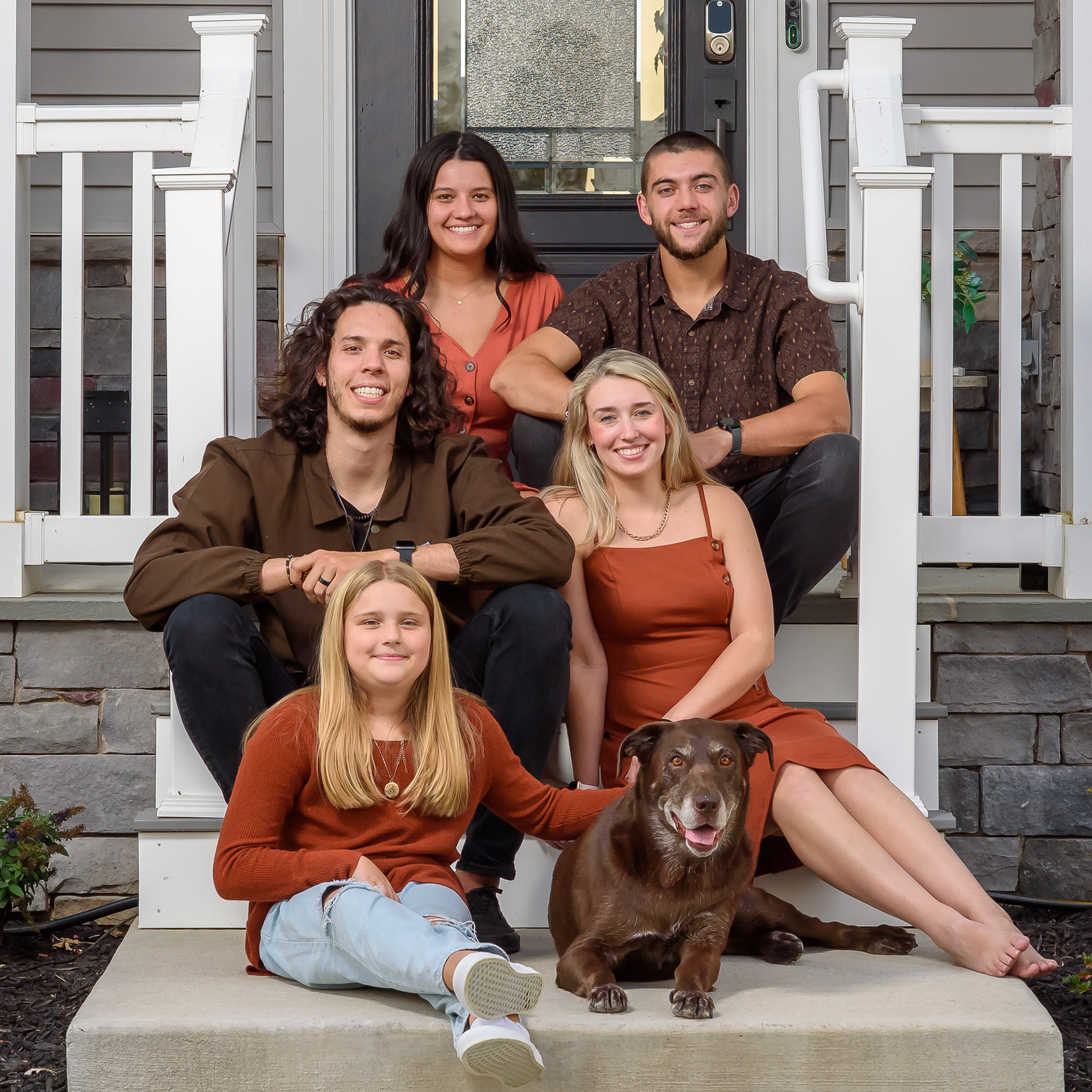 Children of a family on house stairs with dog