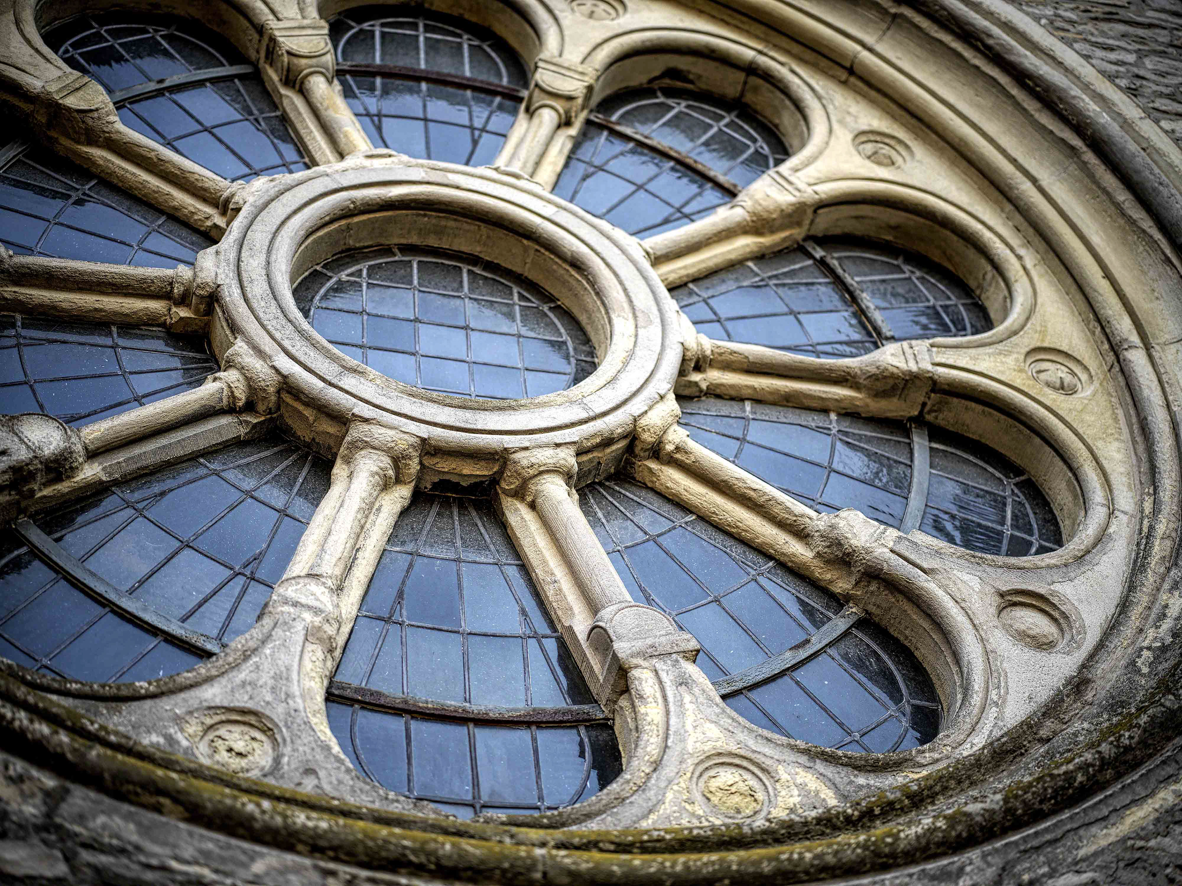 Ein blütenförmiges Fenster in Bleiverglasung. Aufgenommen mit leichtem Bokeh und unerreichtem Detail durch Einsatz der digitalen Mittelformat-Kamera von Hasselblad X1D Mark II. Die Datei ist leicht bearbeitet (Tonung)
