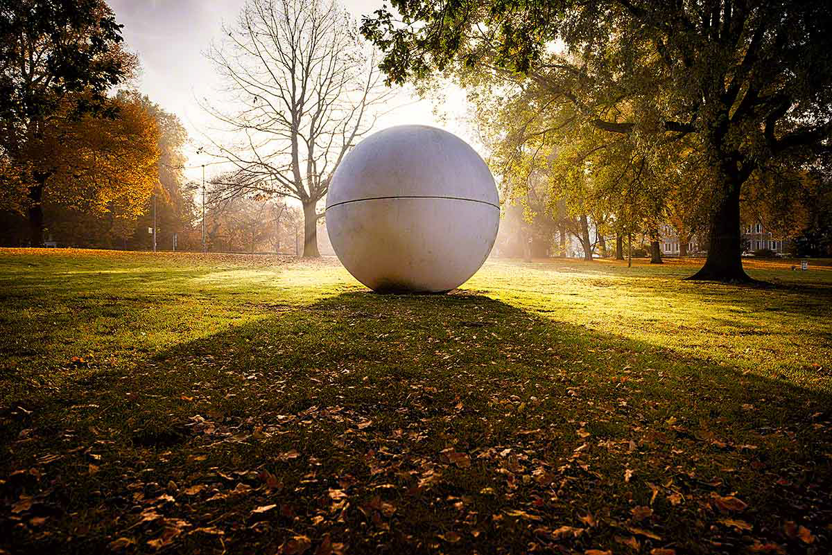 Einer von Claes Oldenburgs Giant Pool Balls am Aasee in Münster in Morgensonne die eine V Form auf den Rasen wirft