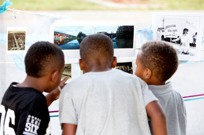 Local kids exploring historical photos curated by Bryant Lee for his neighborhood
