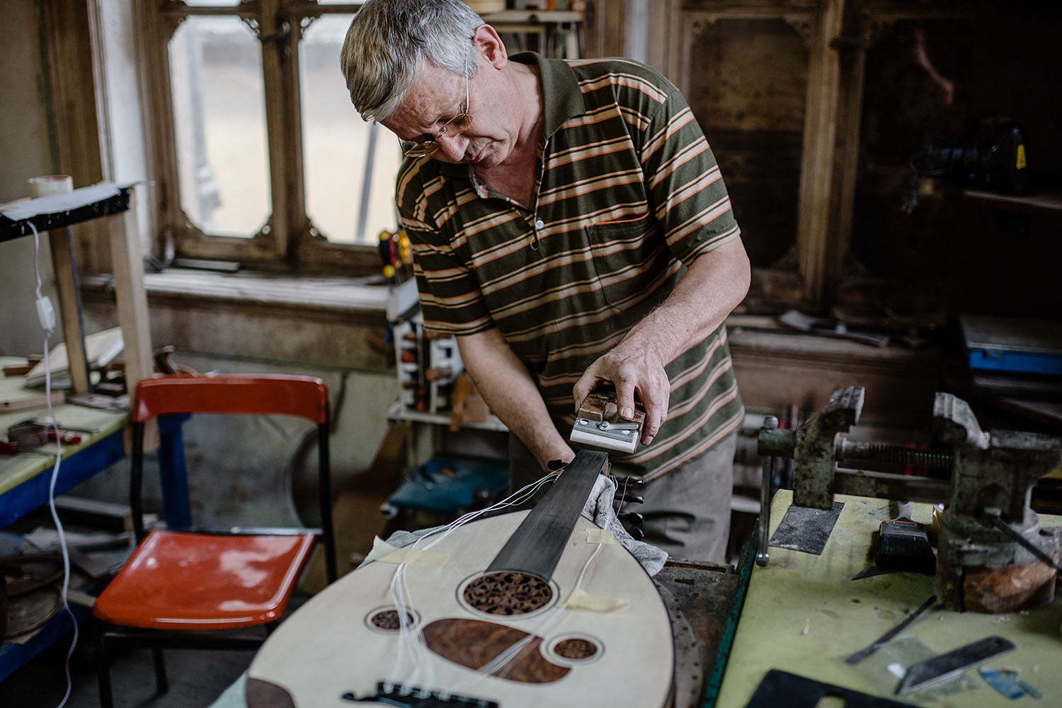 A luthier sanding the surface of a custom oud.