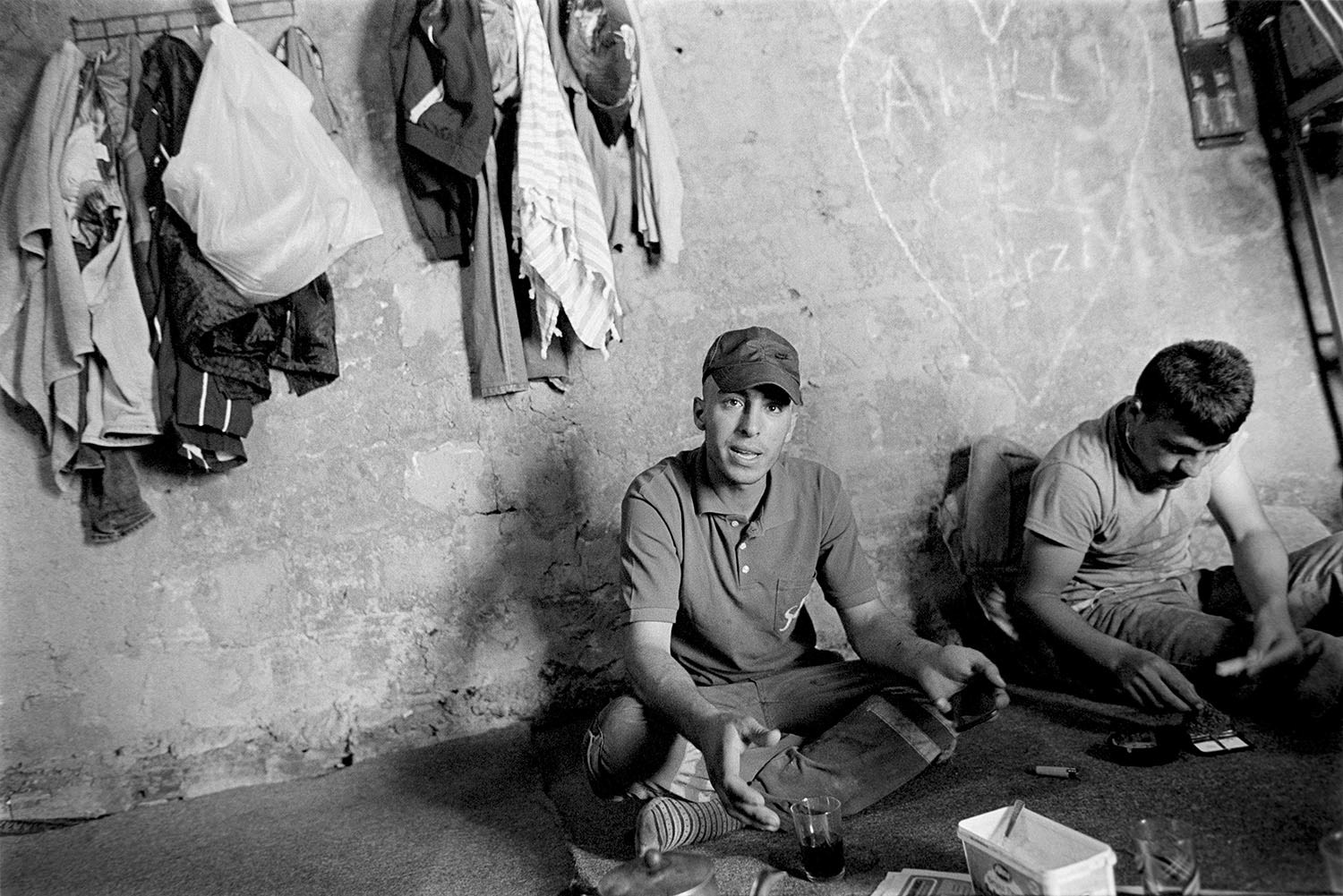 A group of garbage collector boys in their small shack having drinks and talking.