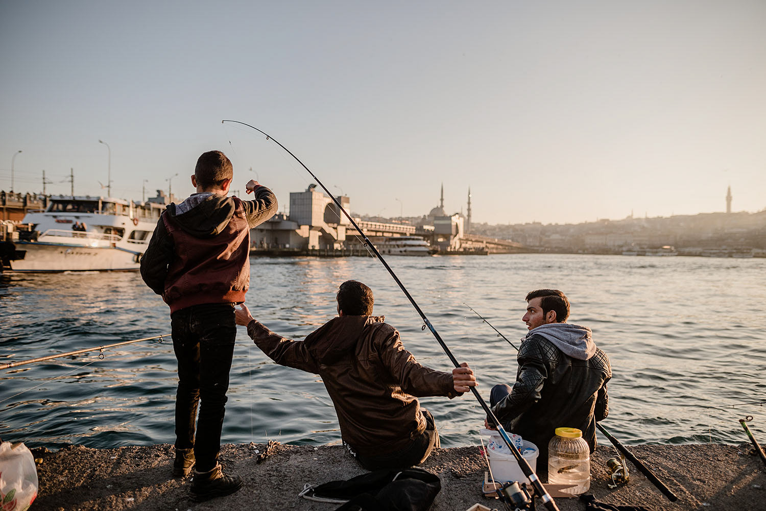 Young people using fishing rods to catch fish by the Haliç Bridge in İstanbul.