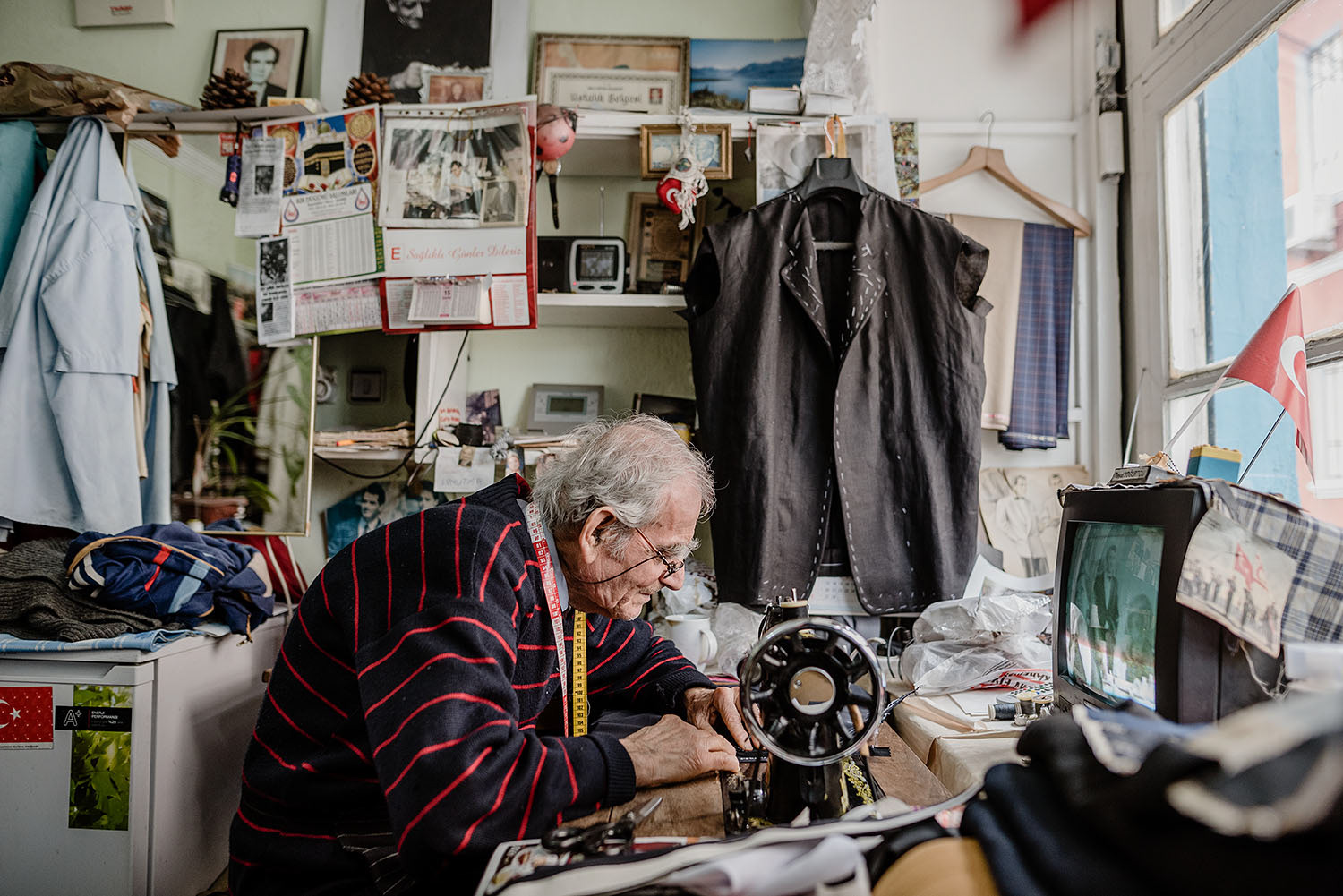 A tailor working on a piece of cloth using his sewing machine.
