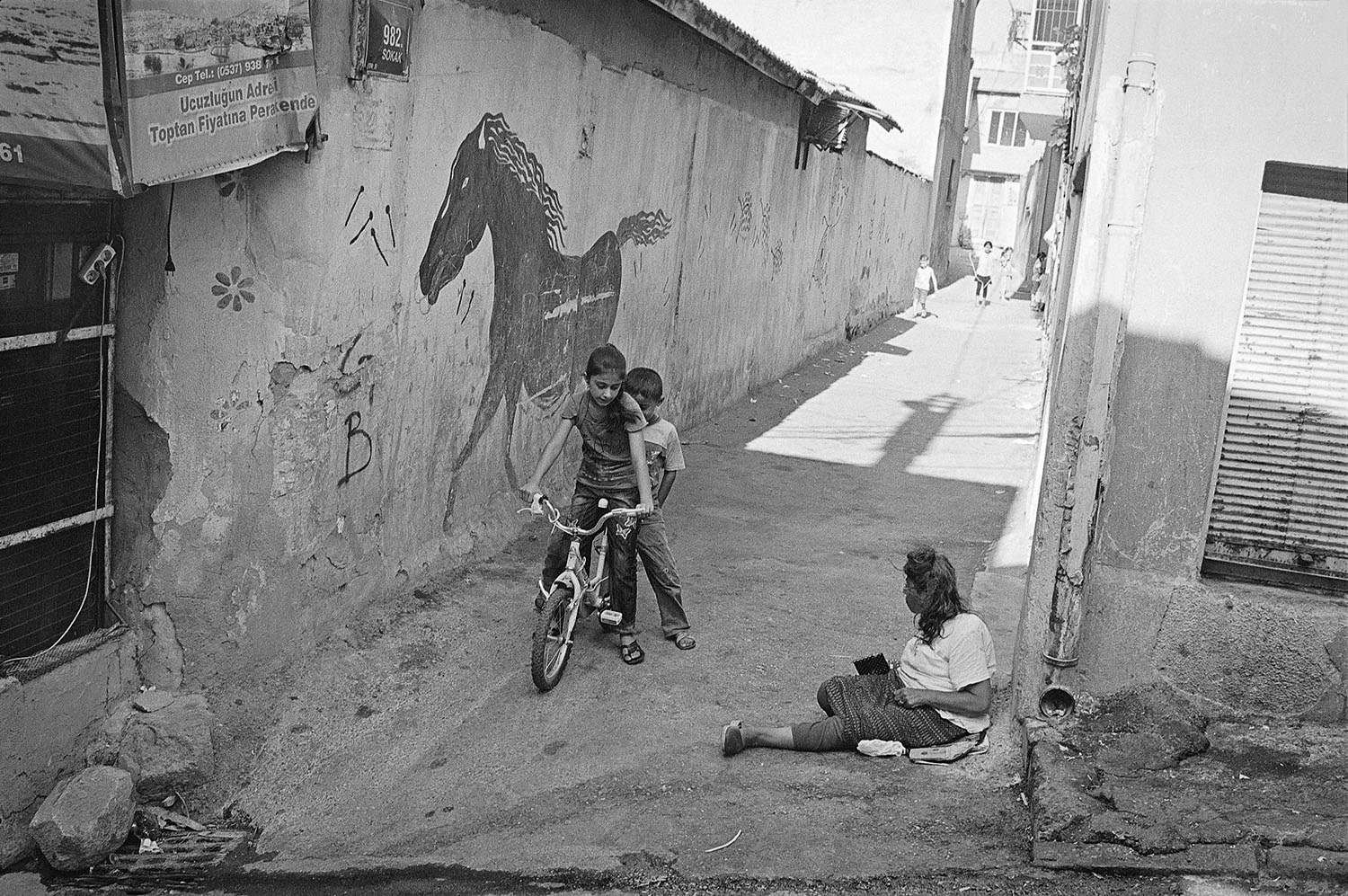 Kids playing and a woman sitting on the ground in Kadifekale Mahallesi in Konak, İzmir Turkiye.