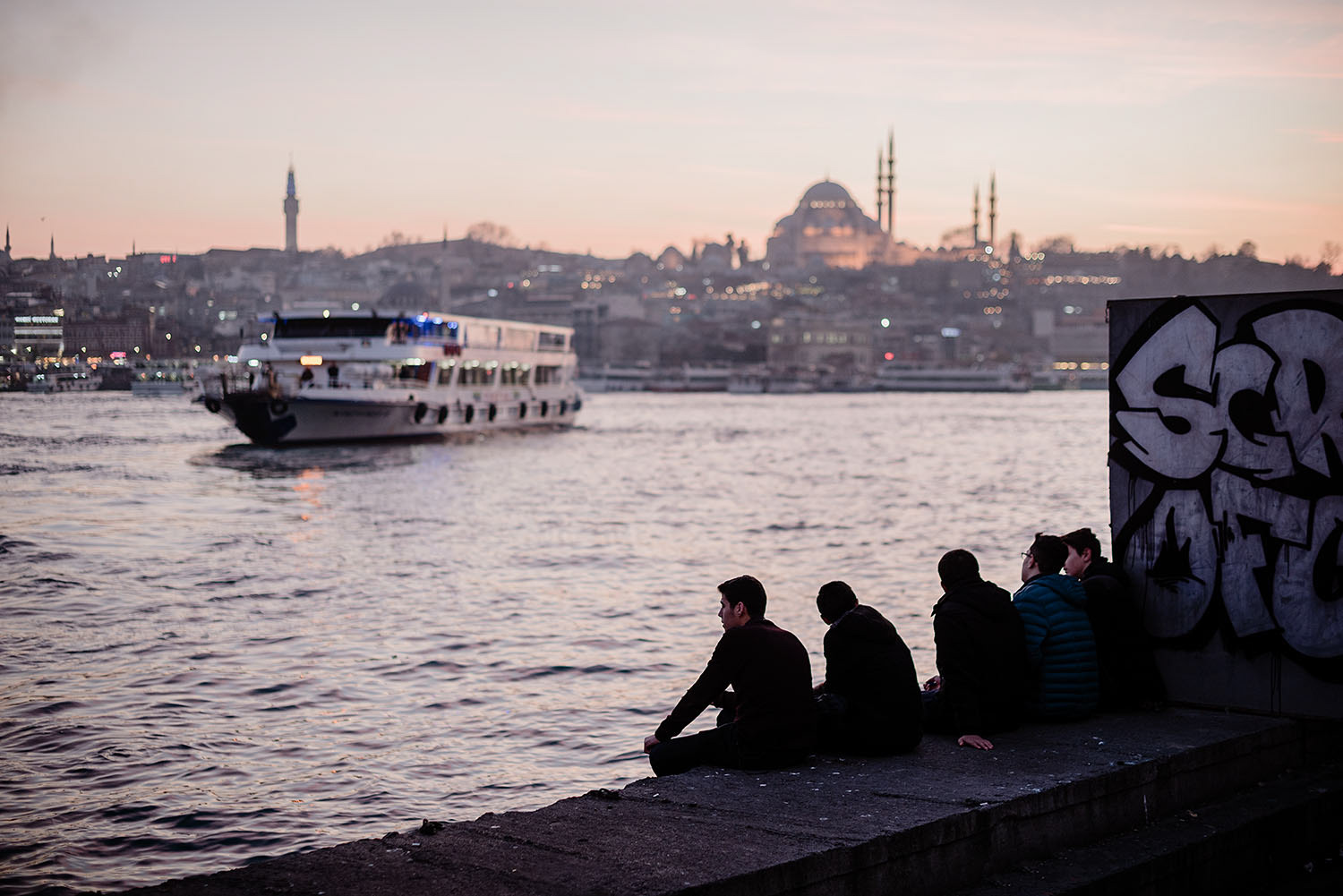A group of young people watching the sea at Haliç while a ferry is leaving the port in İstanbul, Turkey.