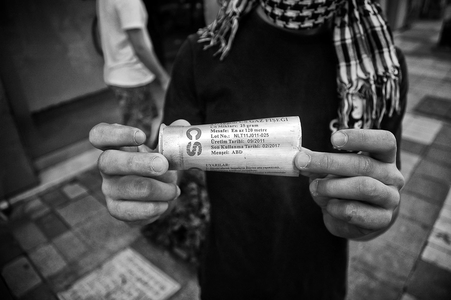A protester is holding a tear gas canister thrown by the riot police.
