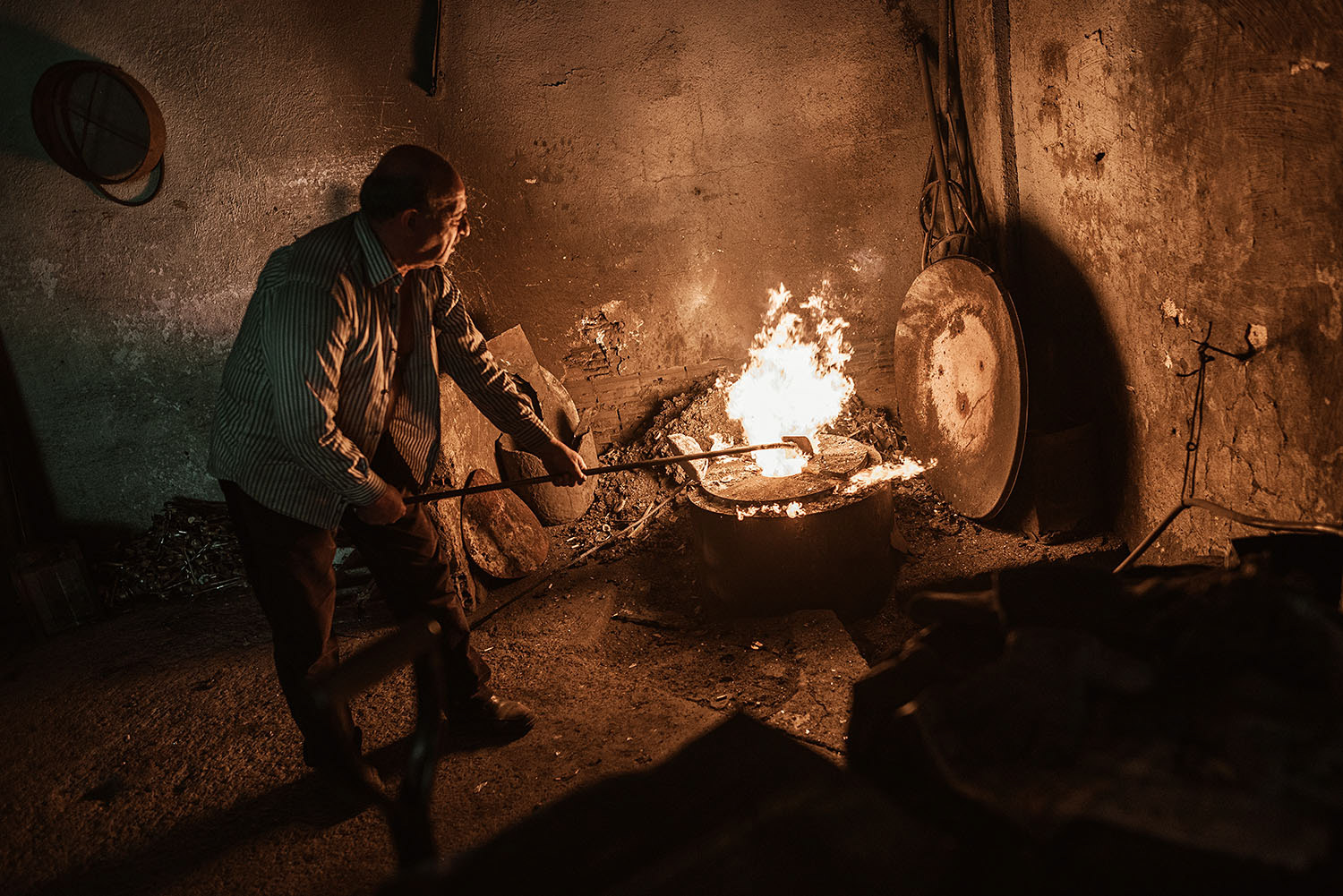A smelter preparing the furnace to melt brass.