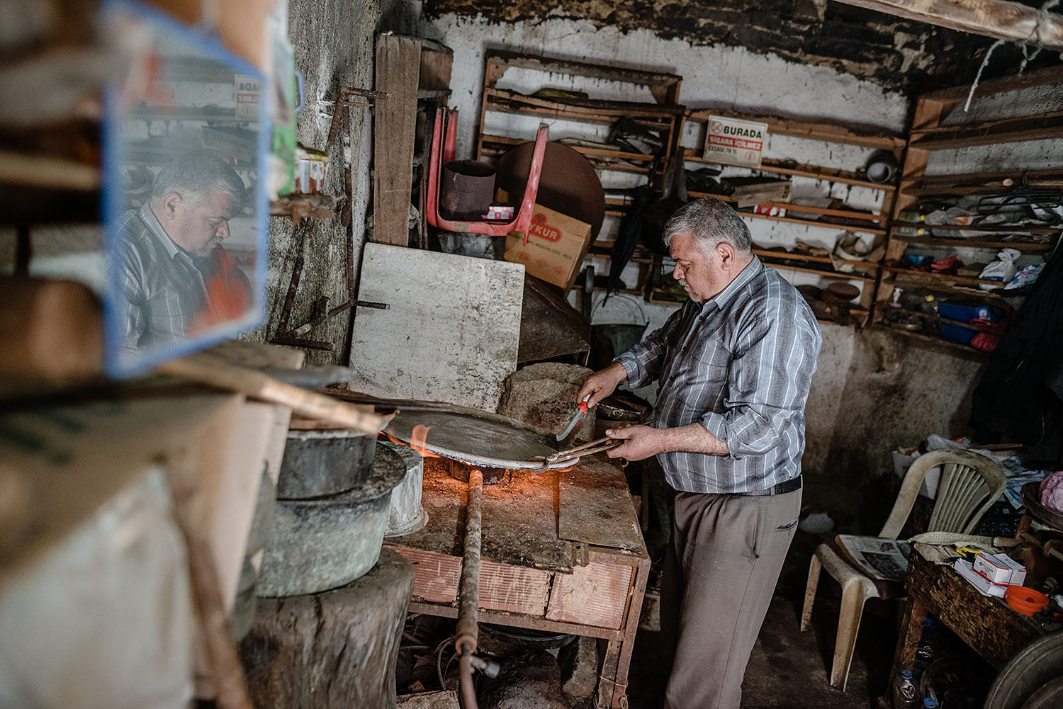 A tinsmith with a large metal piece on the stove.