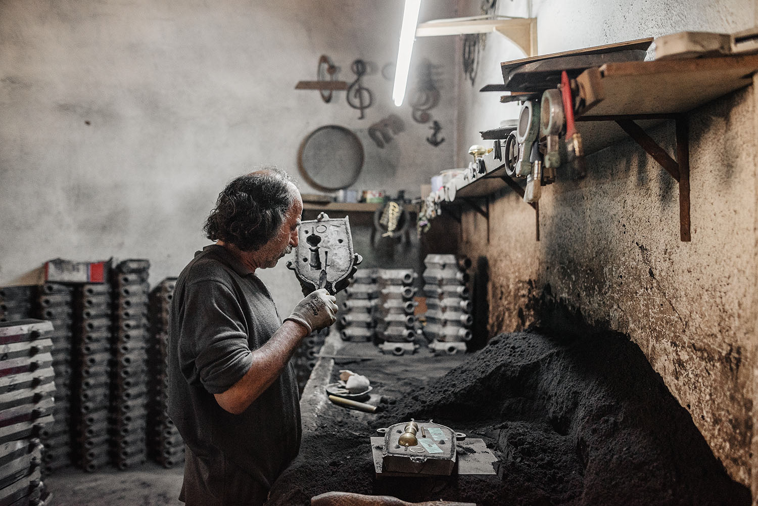 A smelter preparing the sandcasts before pouring molten brass into them.